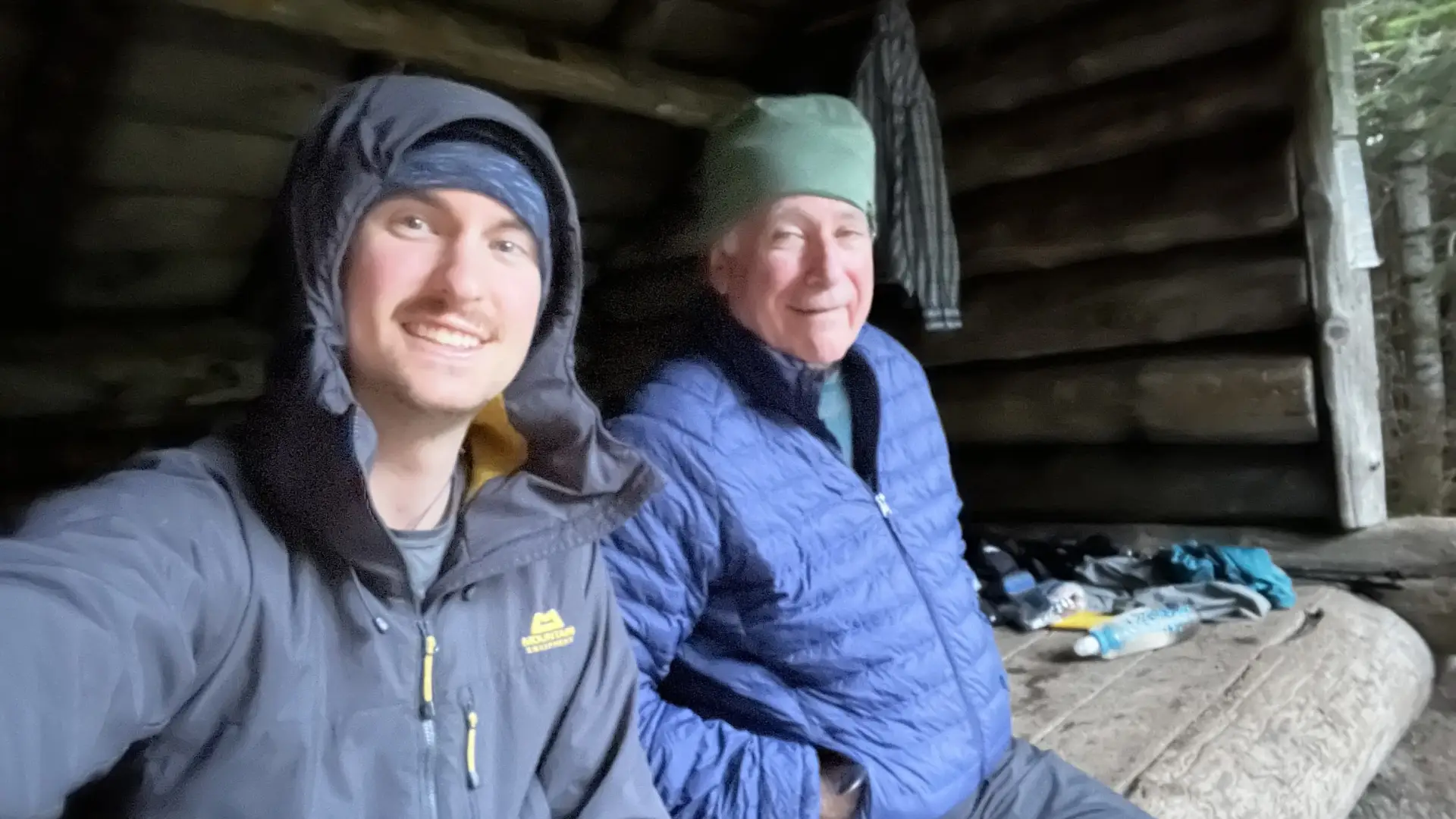 Smiling men sit in a lean to