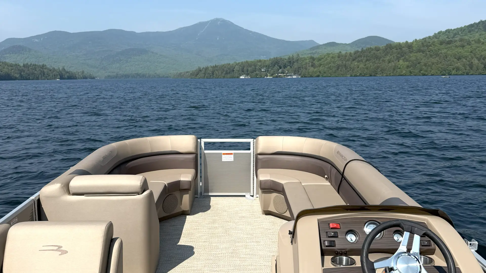 A view of a brown and caramel colored pontoon boat as though you are captaining