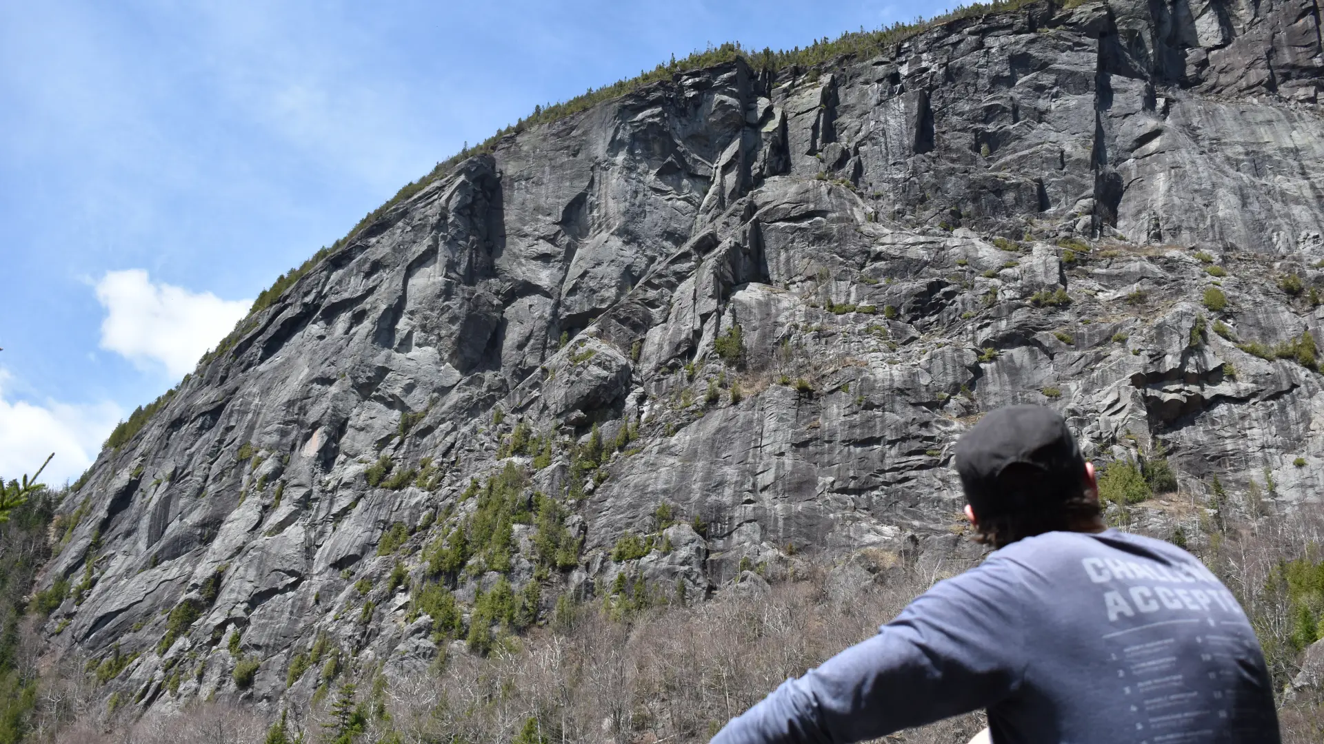 A hiker looking upo at a large rocky cliff