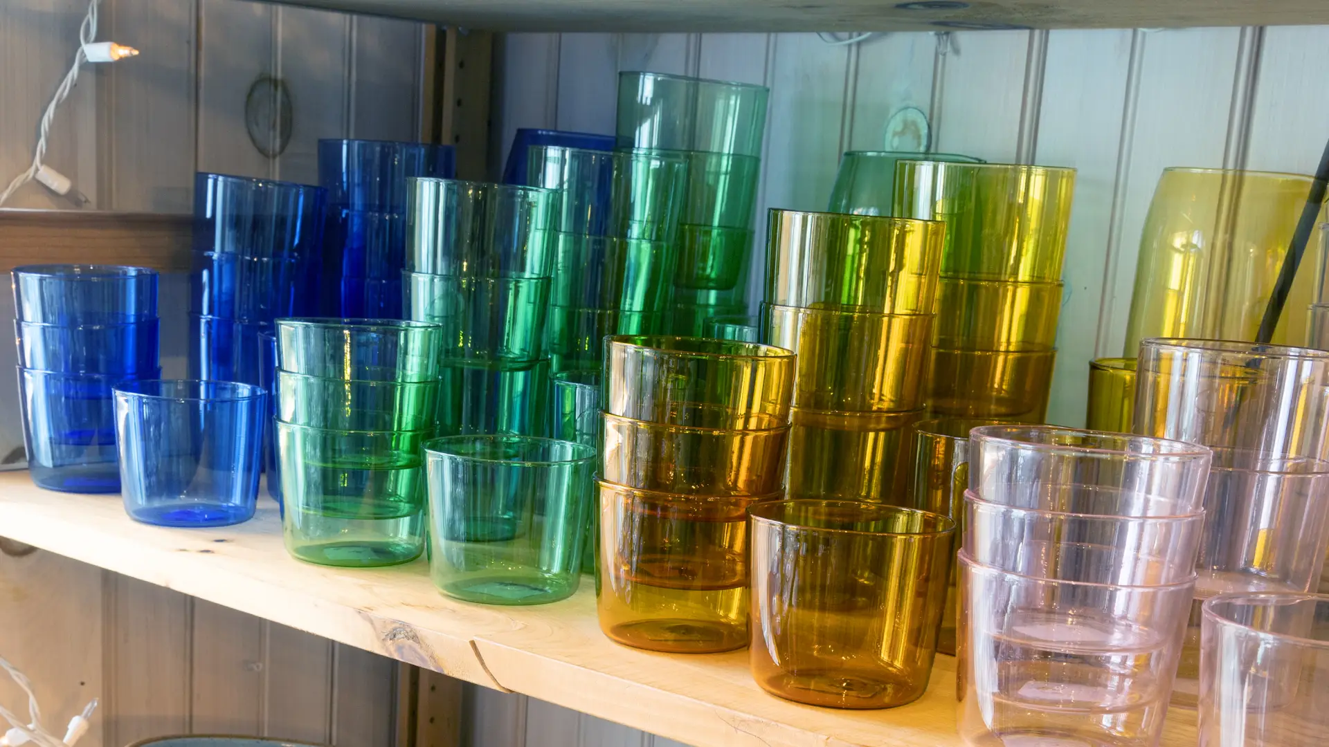 Glasses and bowls in a  wide range of colors fill multiple shelves.