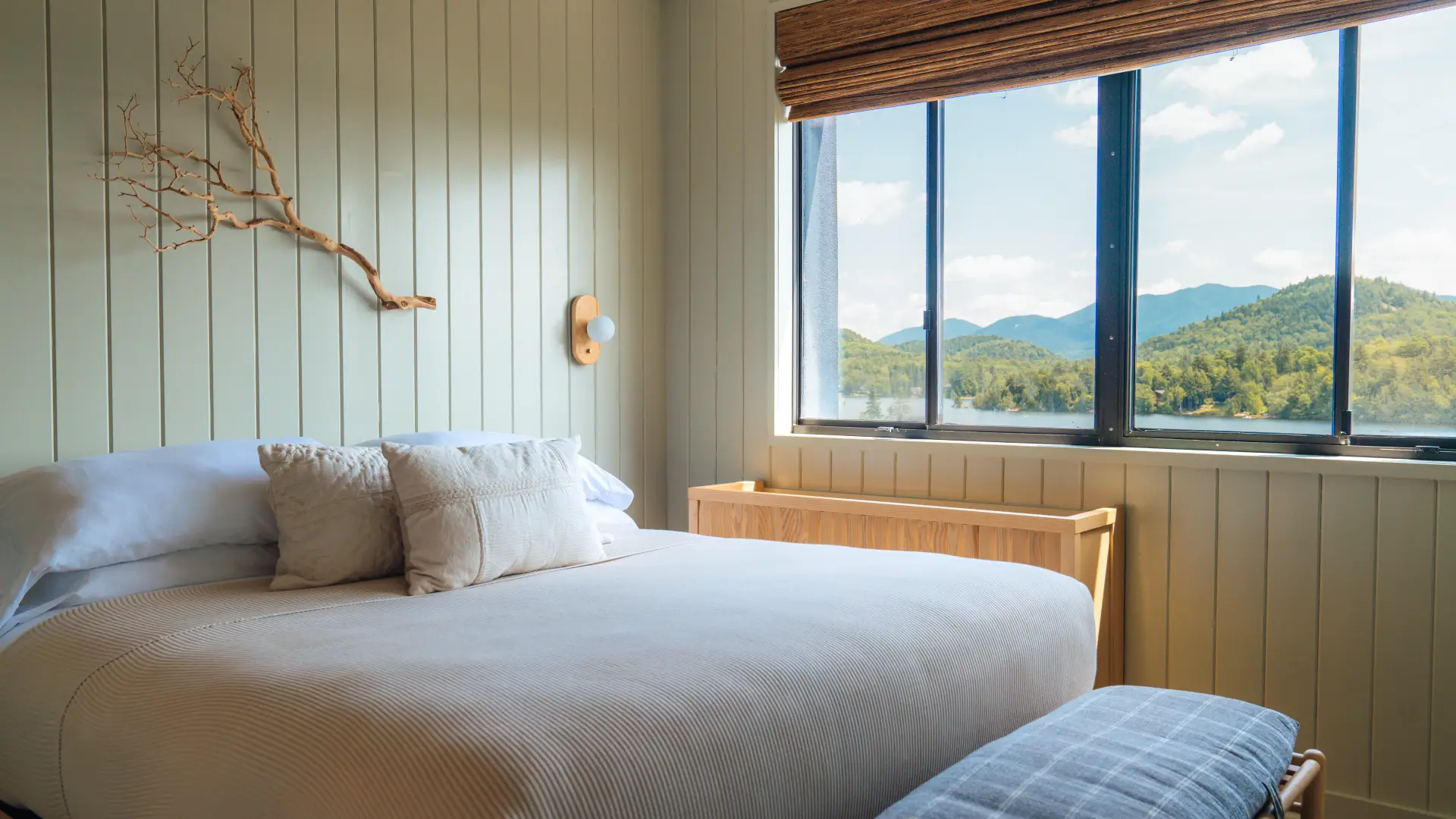A mint green, minimal room at Laurel Lake Placid with light bedding and a view of Mirror Lake and surrounding mountains.