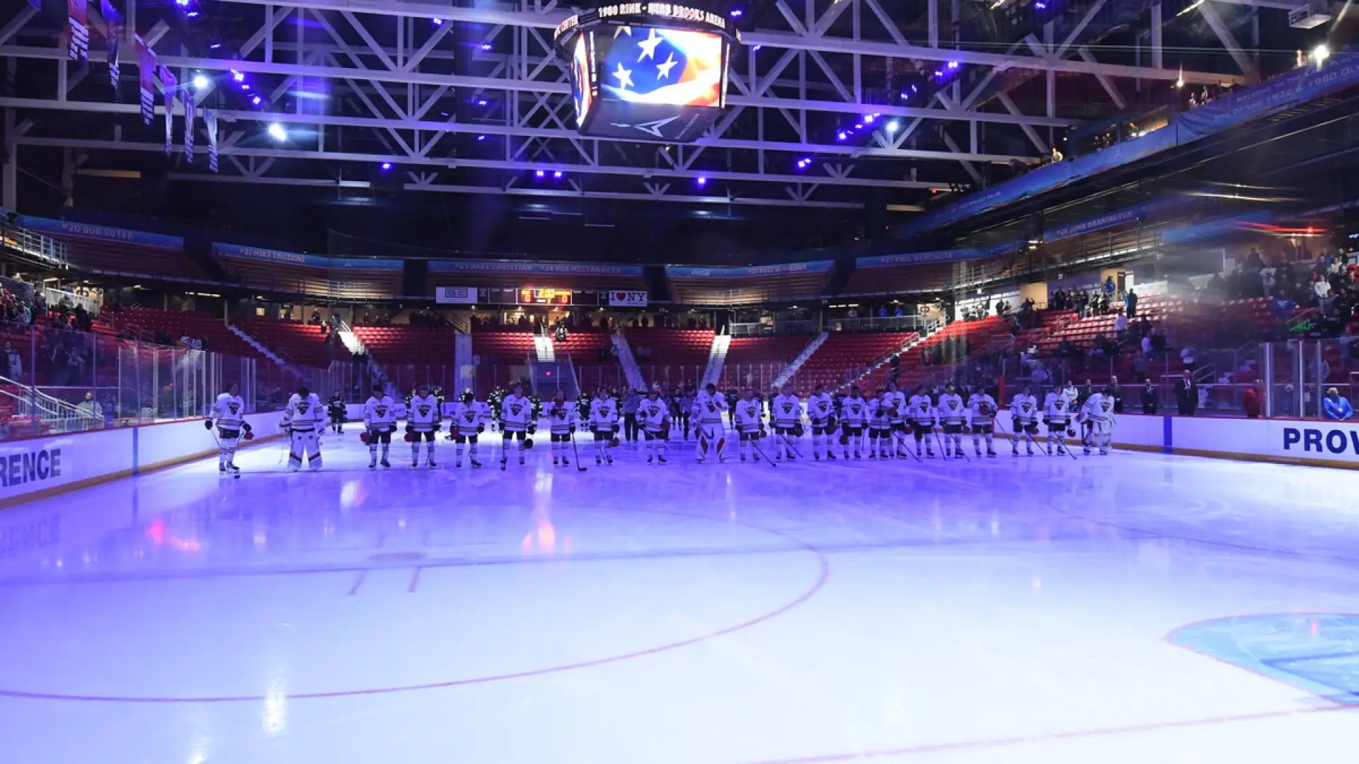Hockey players lined up on center ice in a single file line with the ice illuminated blue in the 1980 Herb Brooks Arena