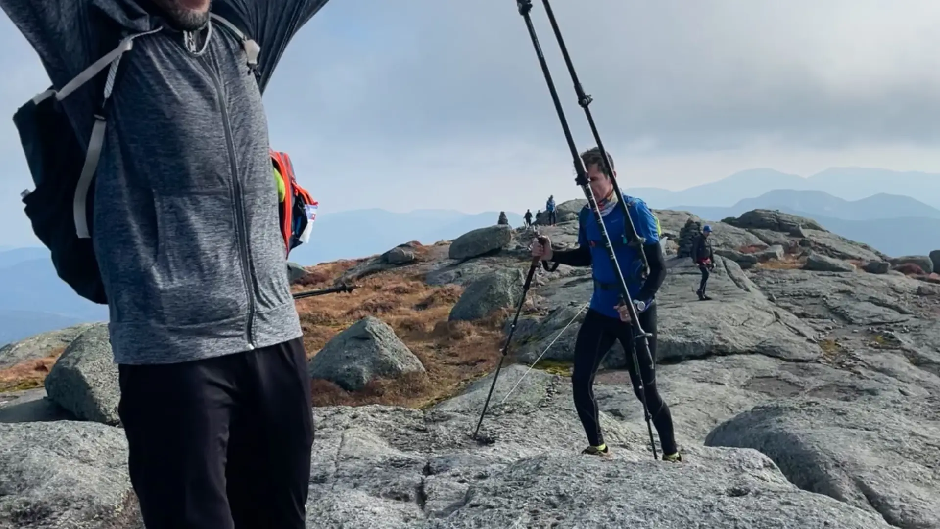A very happy man raises his arm in sucess at the top of the summit