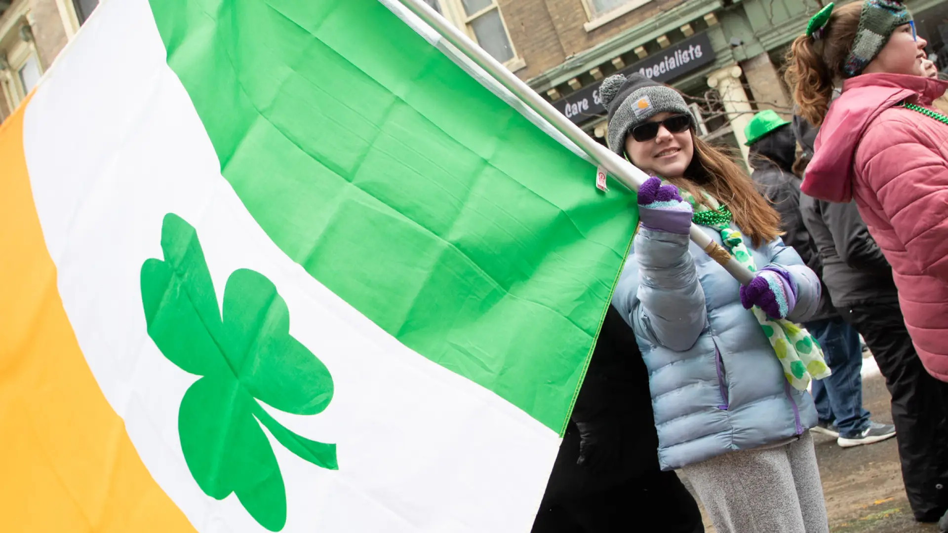 young girl holding irish flag with shamrock at center