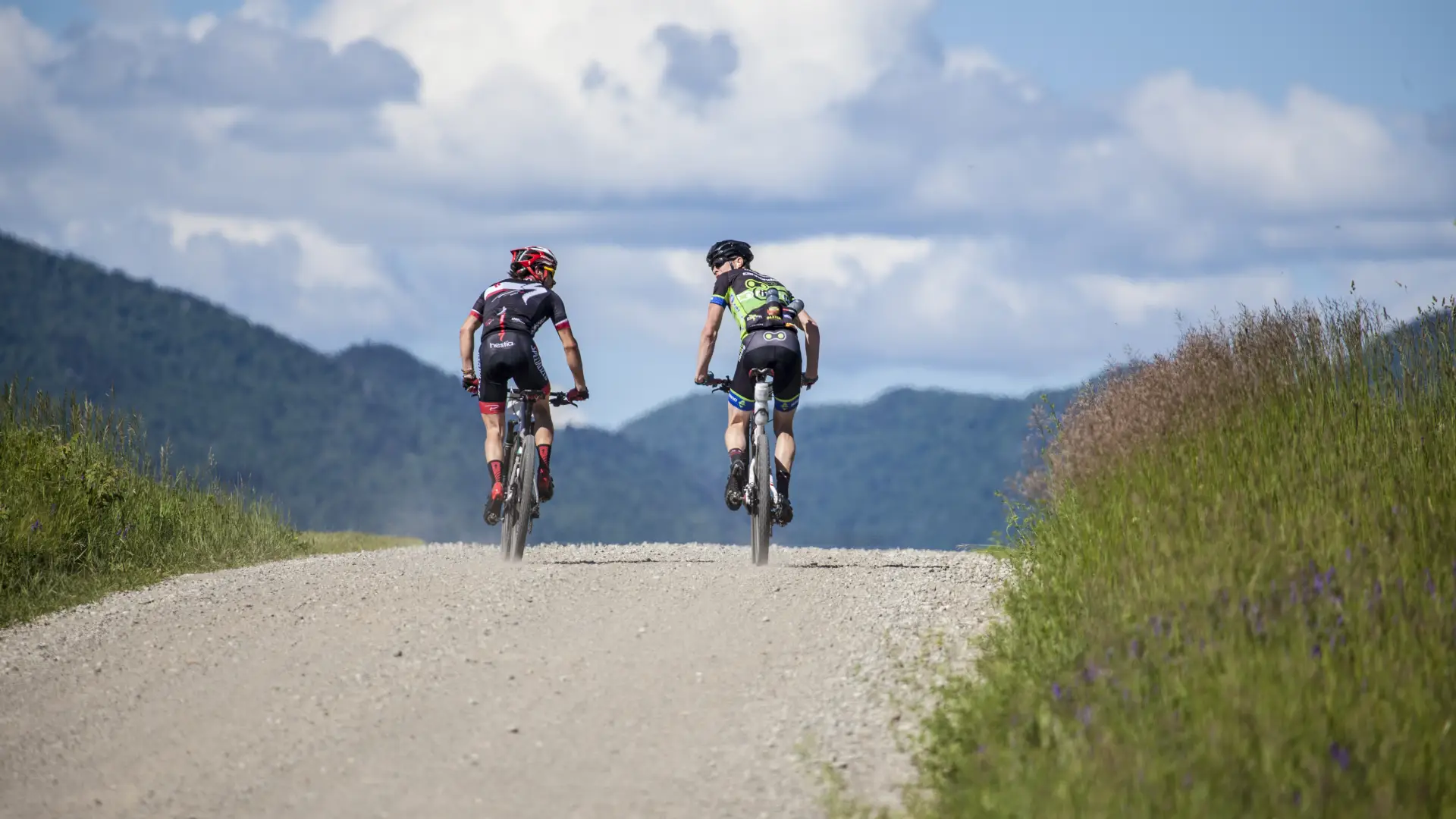 Two cyclists ride on a dirt road