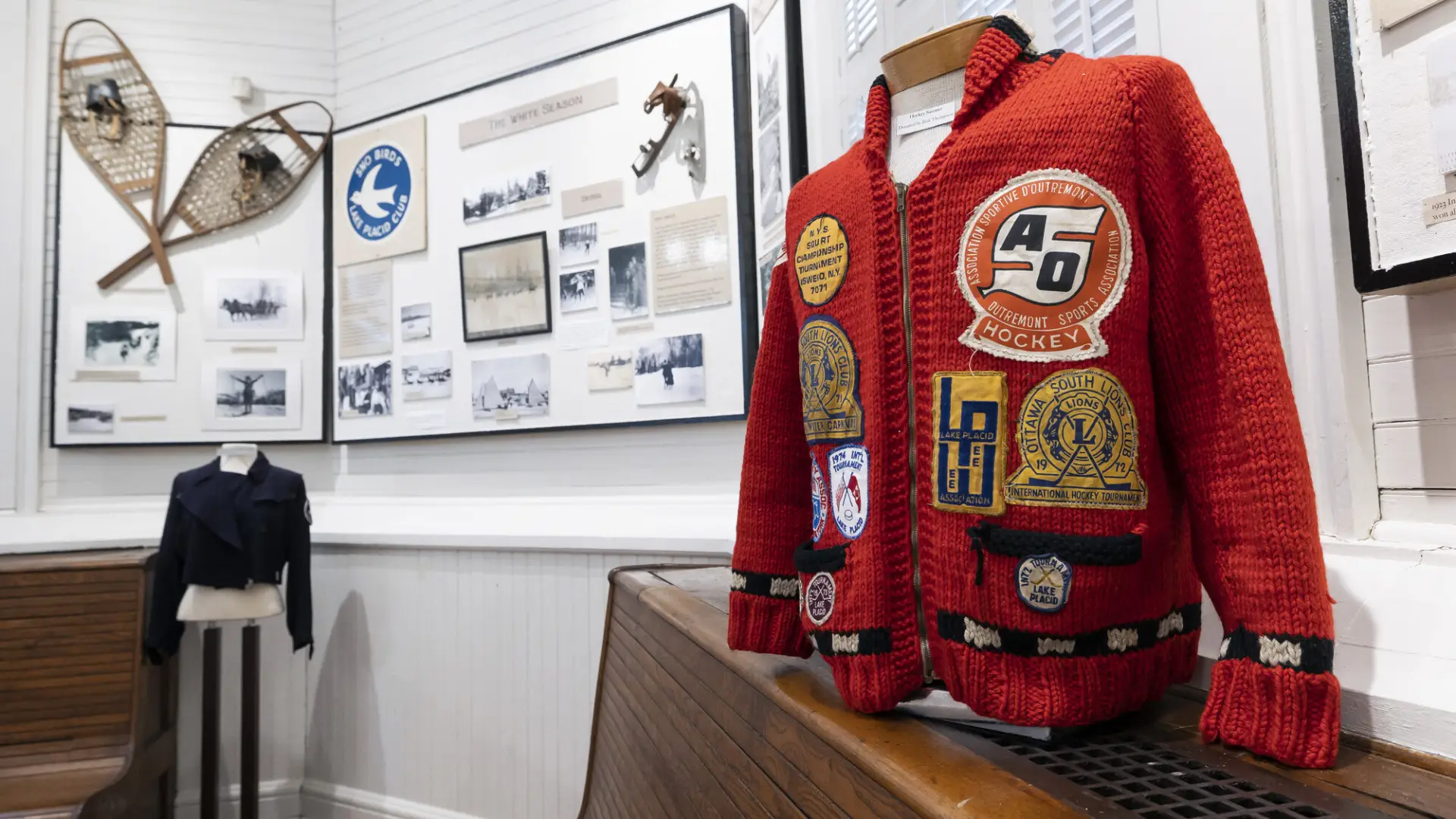 Sweater with patches on display at Lake Placid-North Elba Historical Society & Museum in front of displays on wall