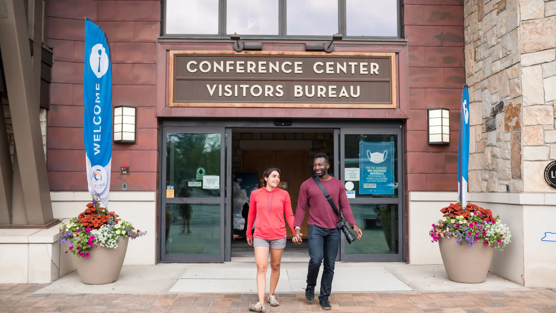 A man and woman walk out of a conference center.