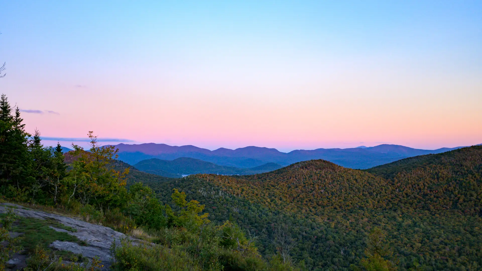 View from the summit of Haystack Mountain Mountain as the sun sets behind the silhouette of the Adirondack Mountains