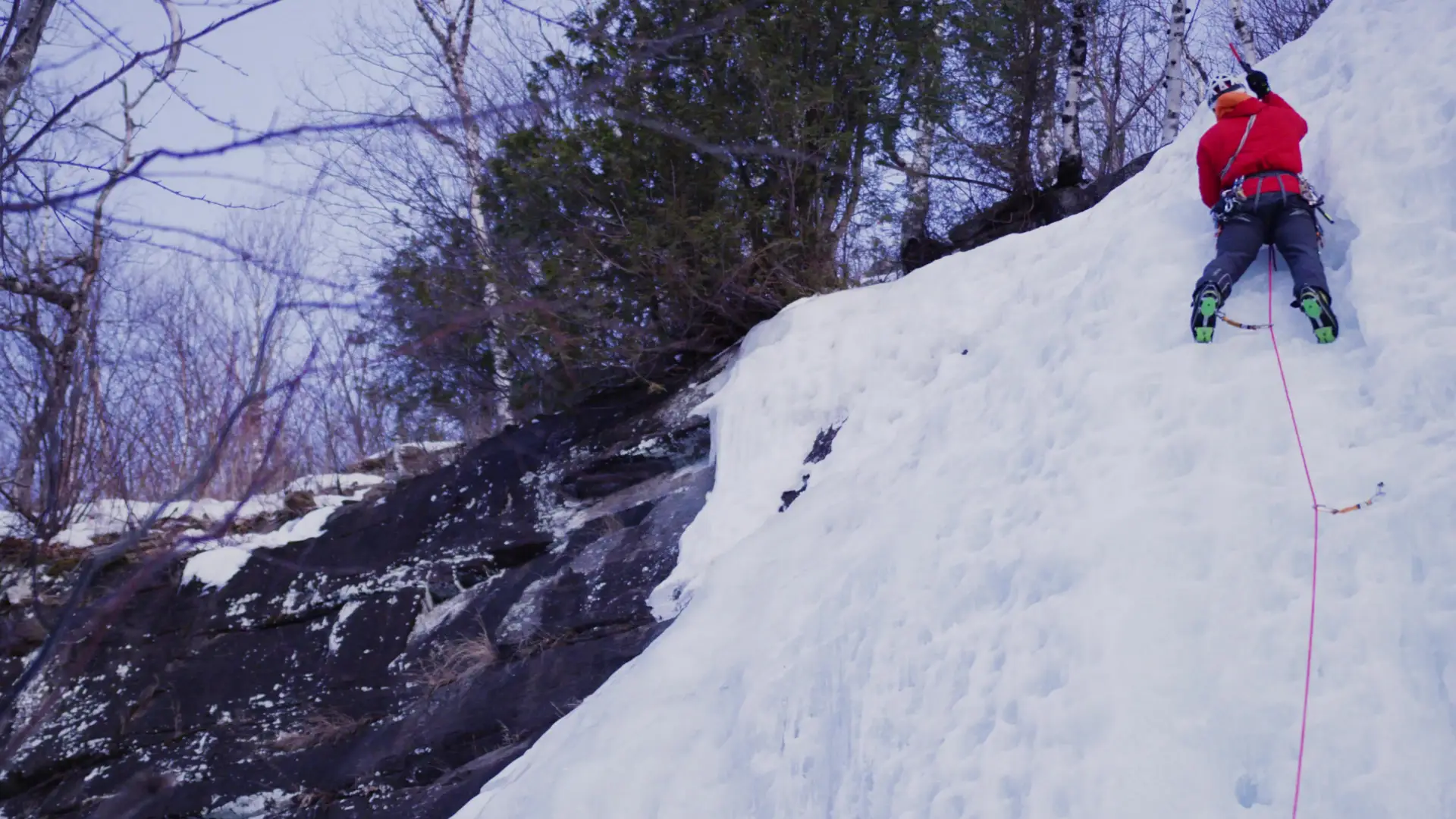 Man swinging ice axe on a wall of ice