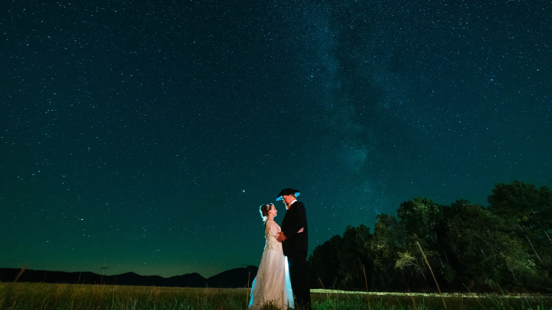 Bride and groom embrace below the milkyway