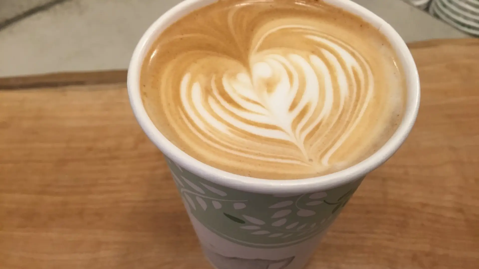 A latte in a paper cup on a table in one of Lake Placid's coffee shops
