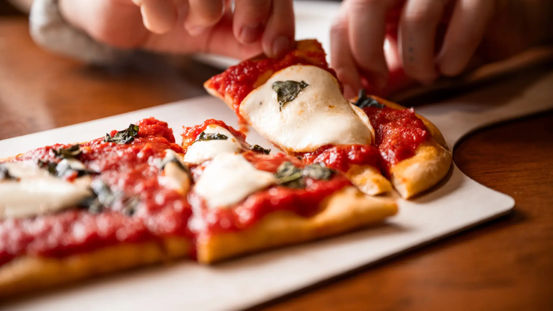 Pizza being pulled from a tray.