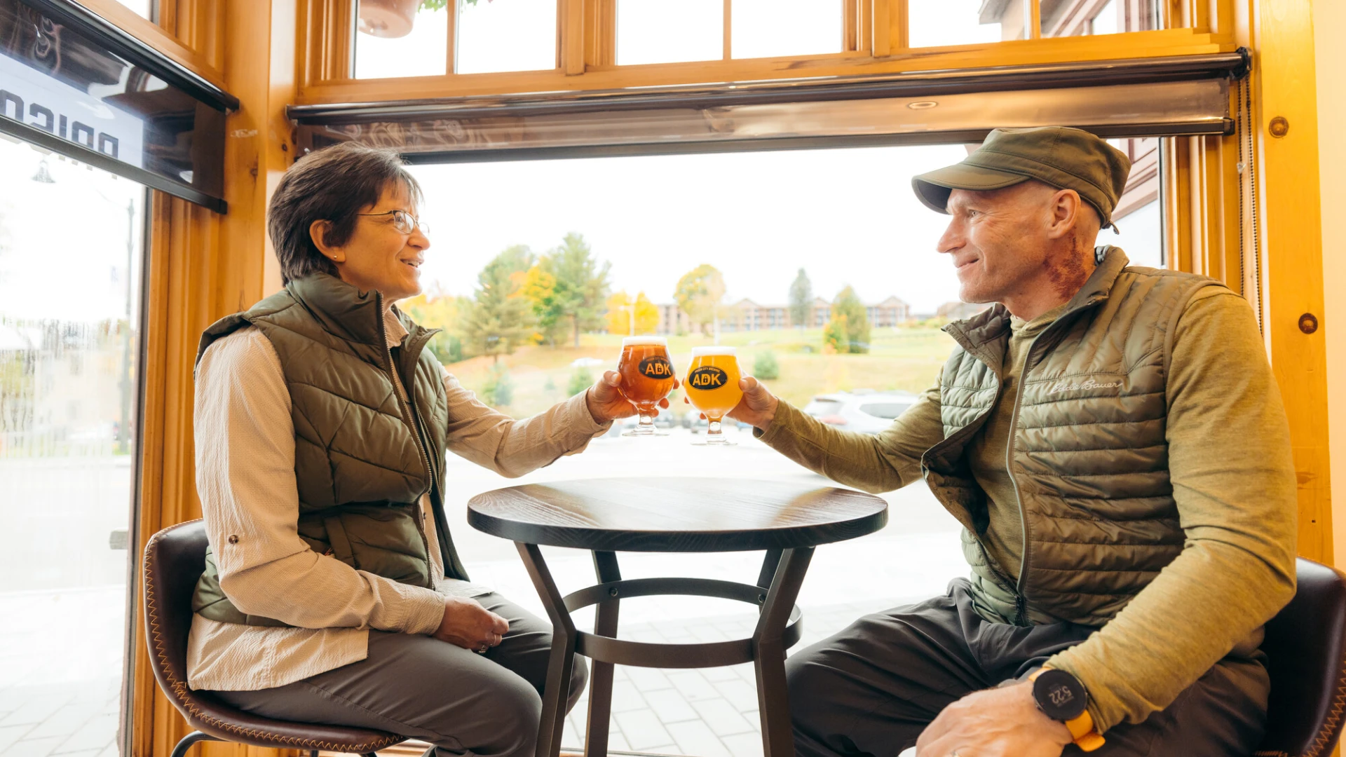 A man and woman cheers beers together at a brewery.