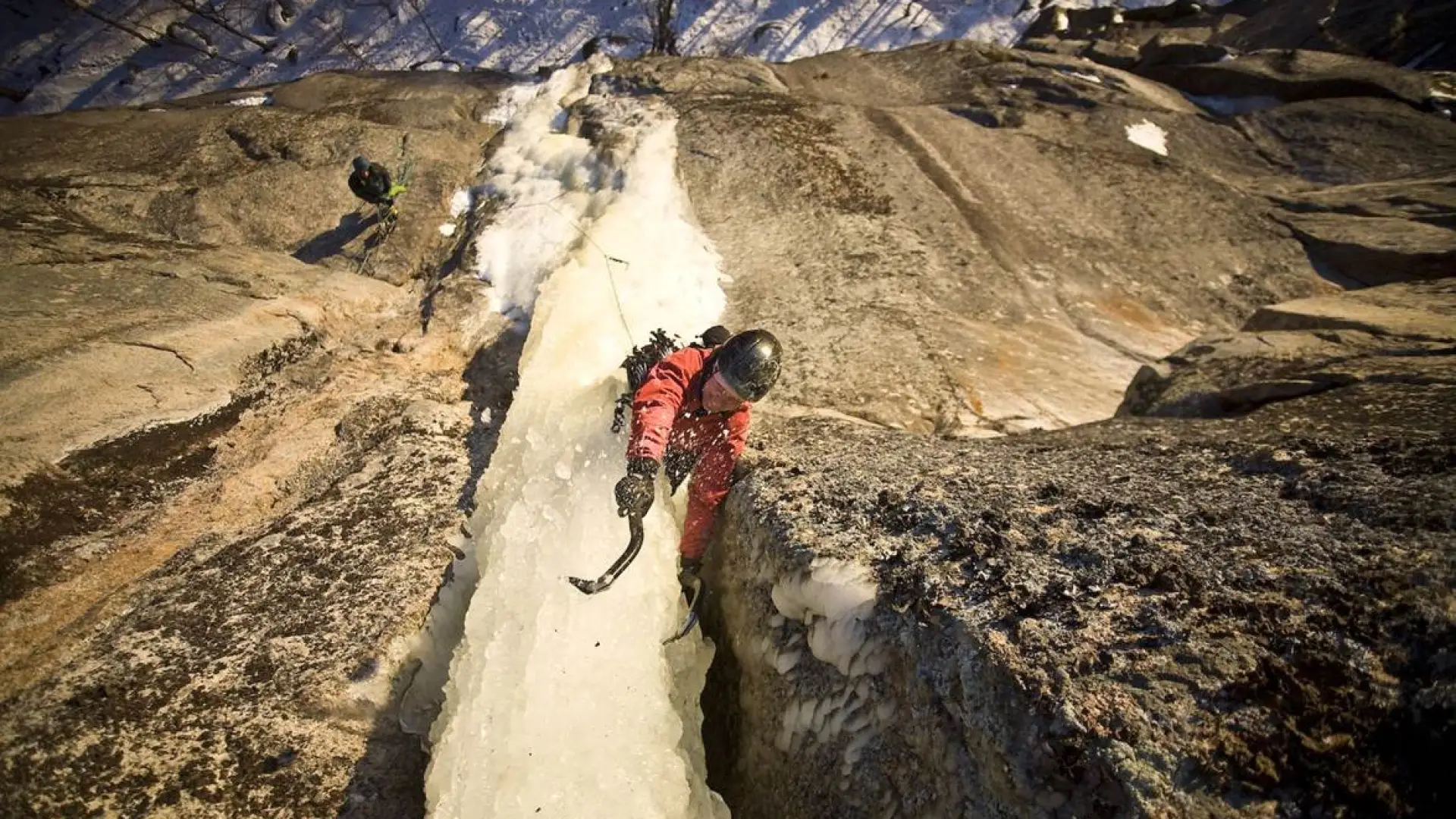 A person ice climbing a narrow dagger of ice