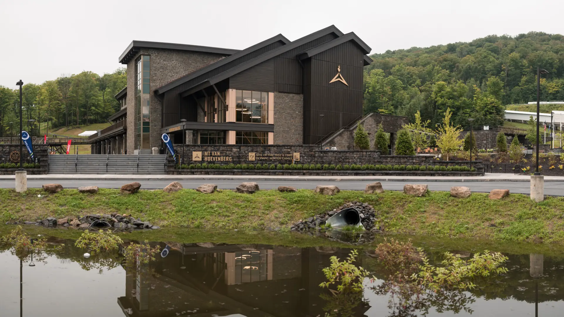 The new, modern Mountain Pass Lodge is classic Adirondack rustic design with a modern twist. It is surrounded by trees and hills.