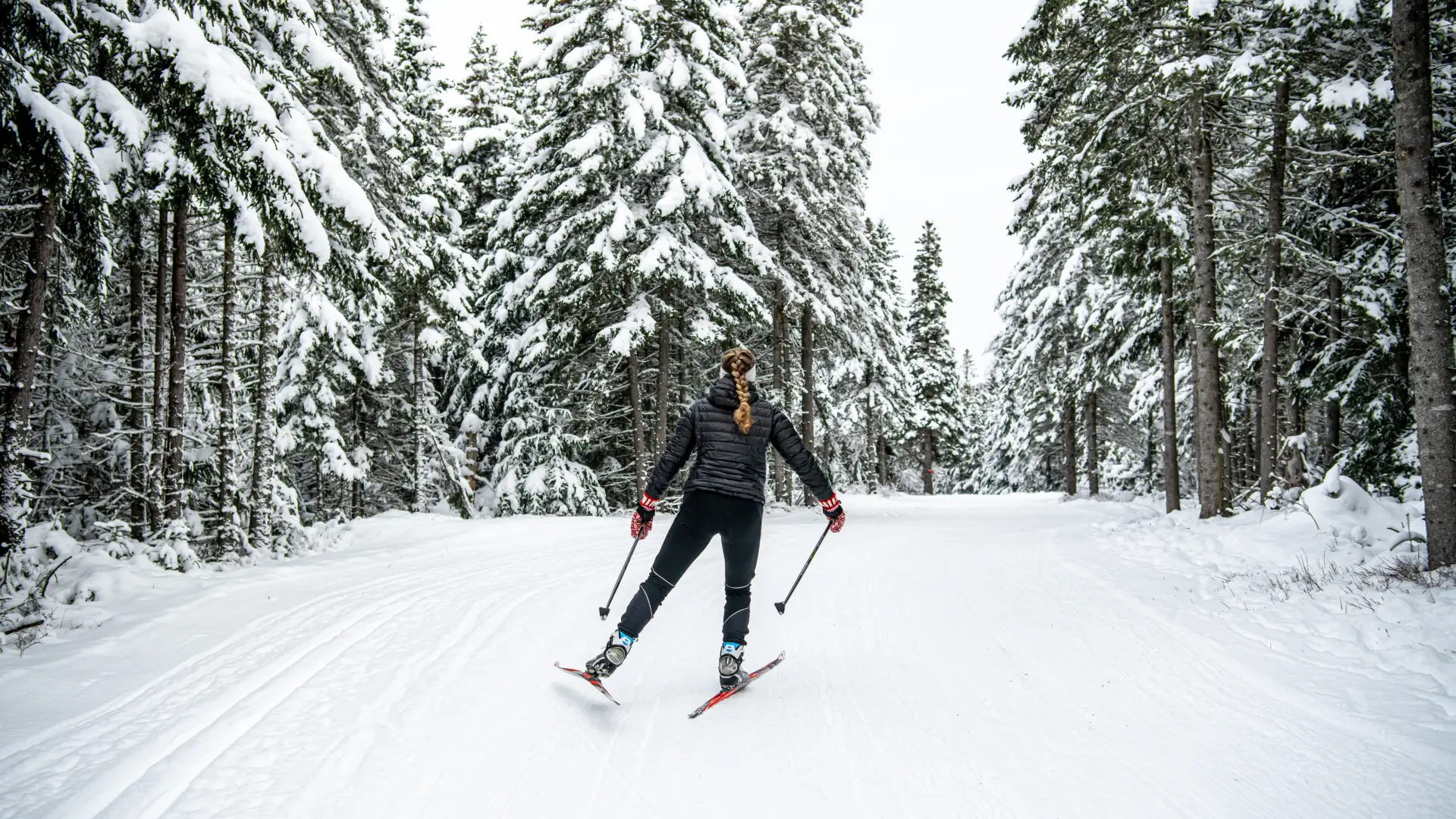 Woman cross-country skiing on snowy trail.