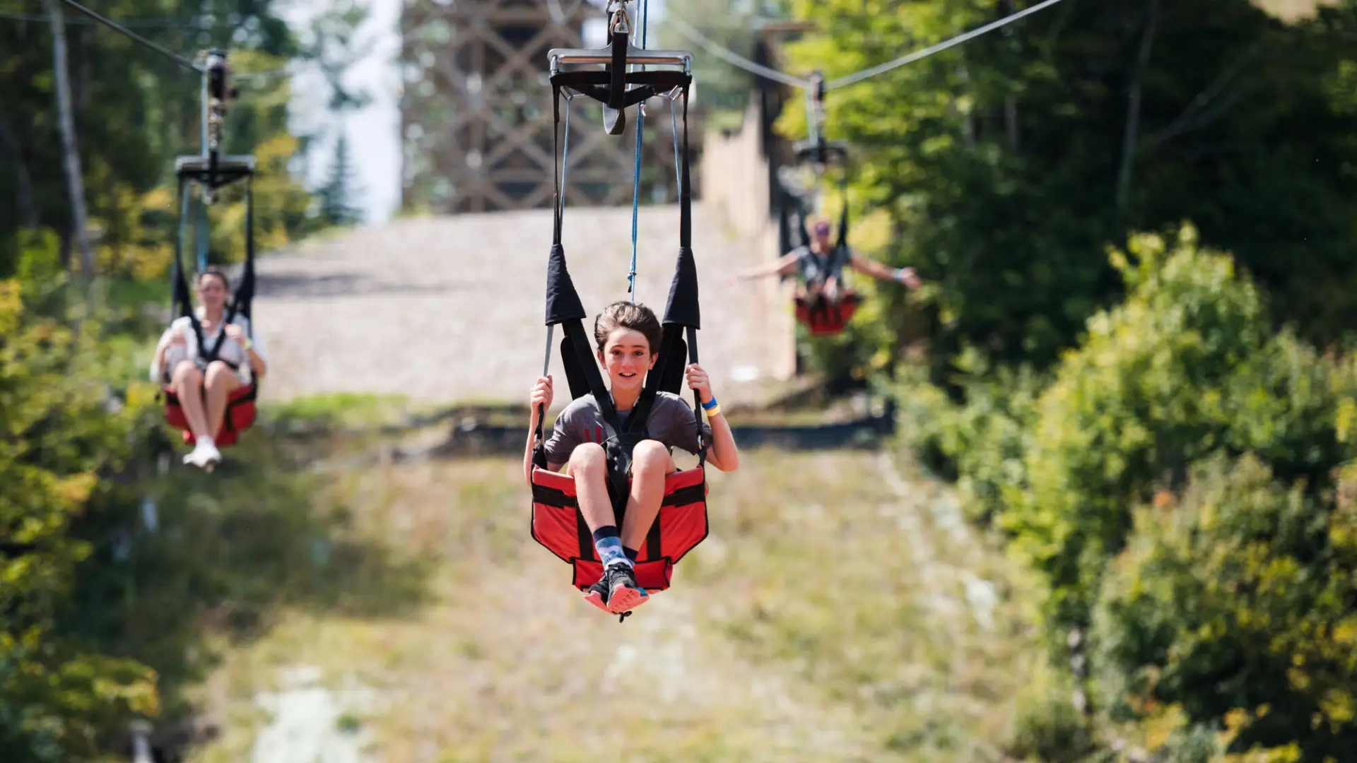 A young boy glides down a zipline. 