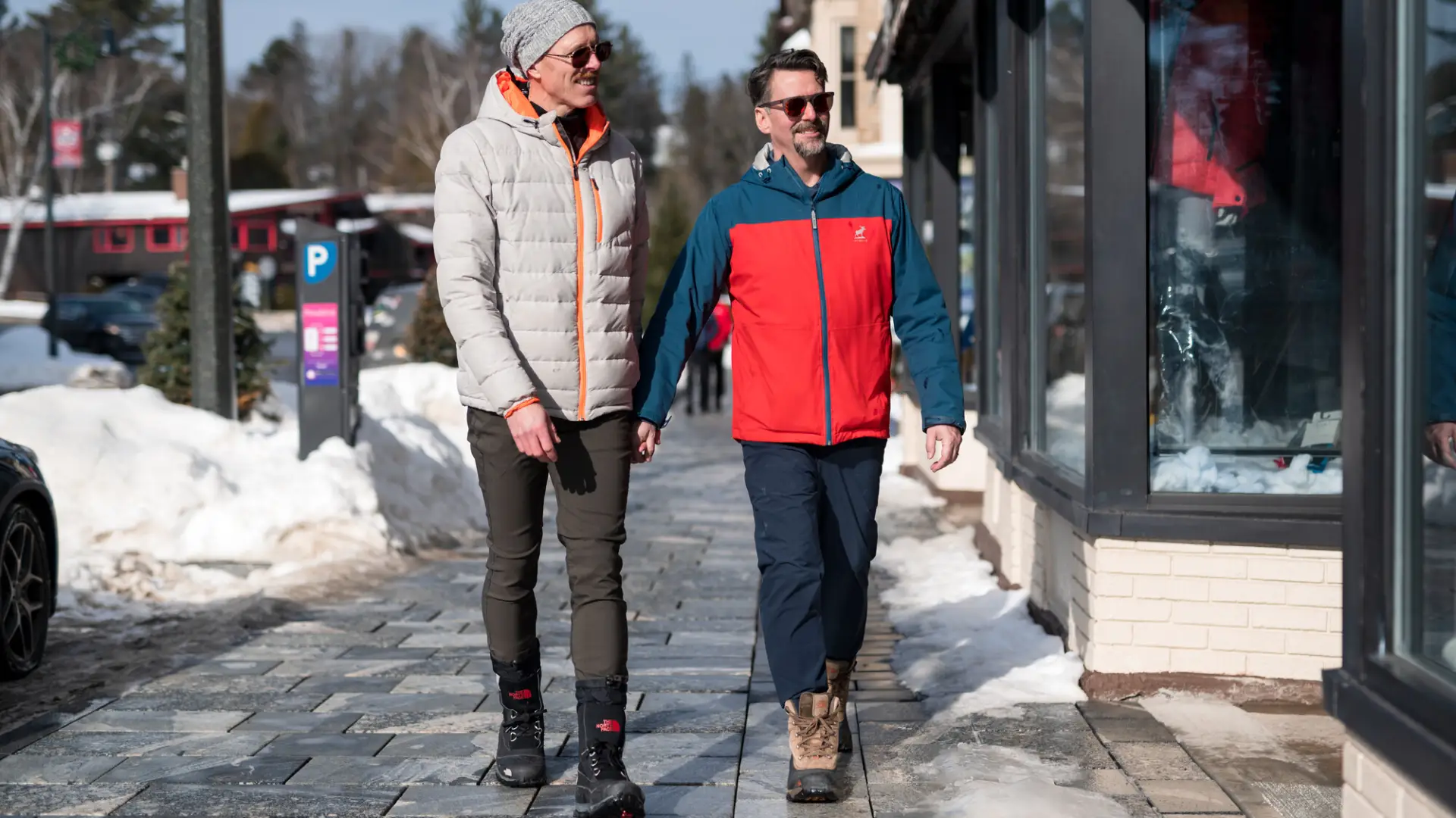 Two men walk on Lake Placid Main Street in winter on a sunny day.