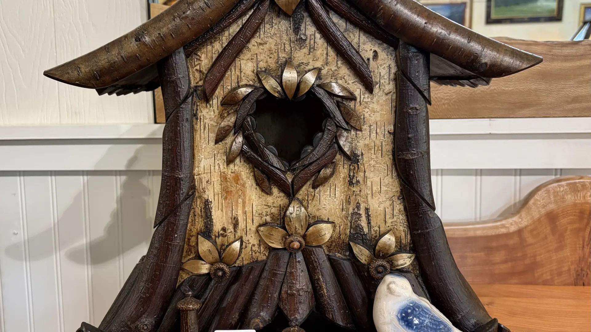 A rustic birdhouse made from twigs, birch bark, pine cones and various natural materials.