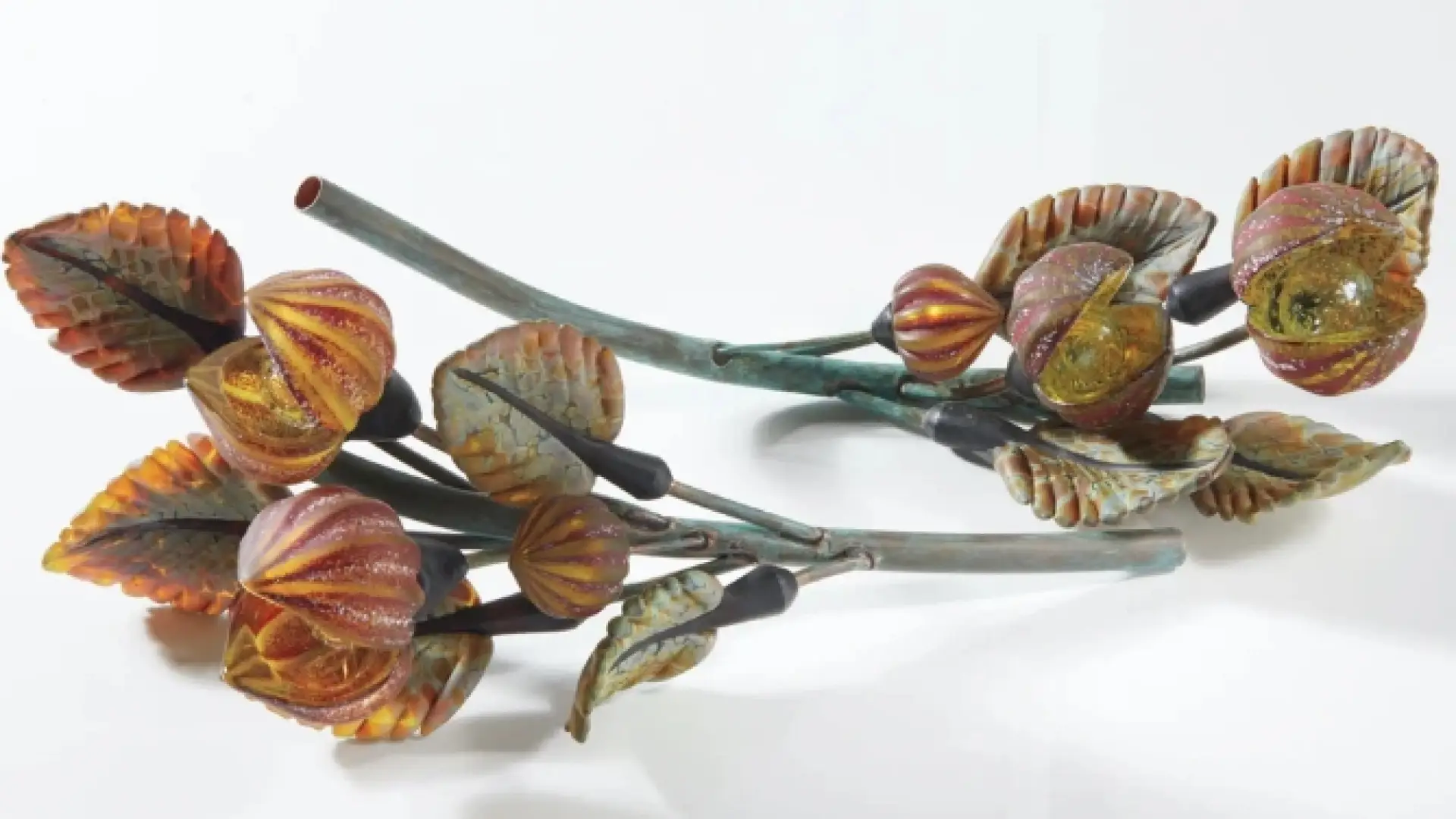 Two flowering branches made of unknown material lie on white surface faced in opposing directions