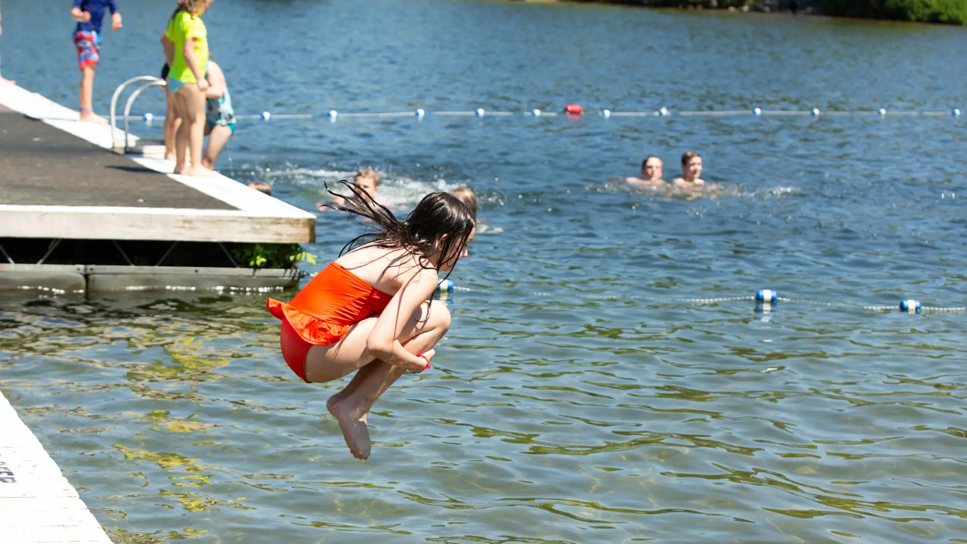 A young girl jumping into a lake.