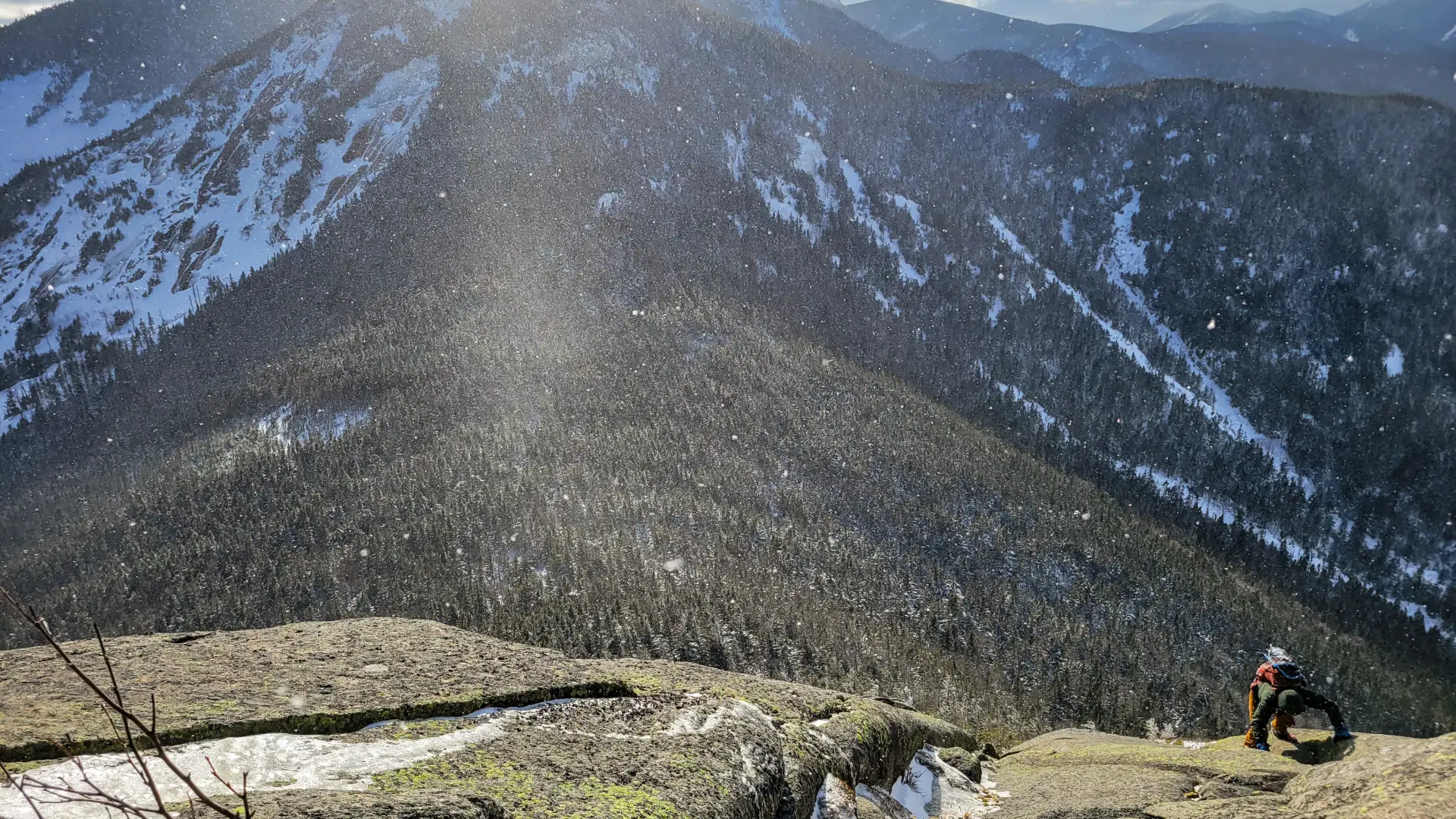 A hiker ascends a cliff in the mountains