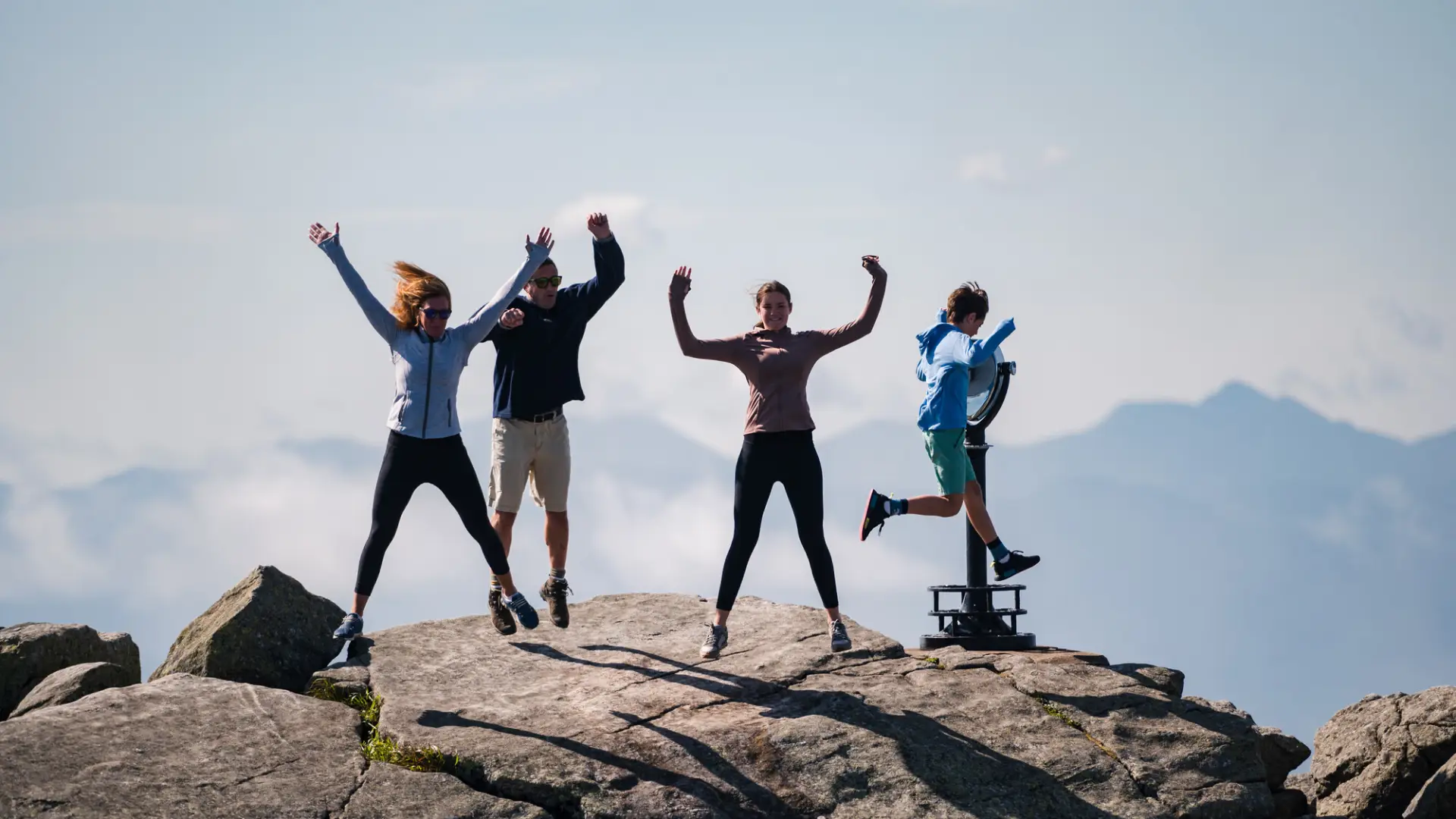 A family jumps for joy on top of a rocky mountain