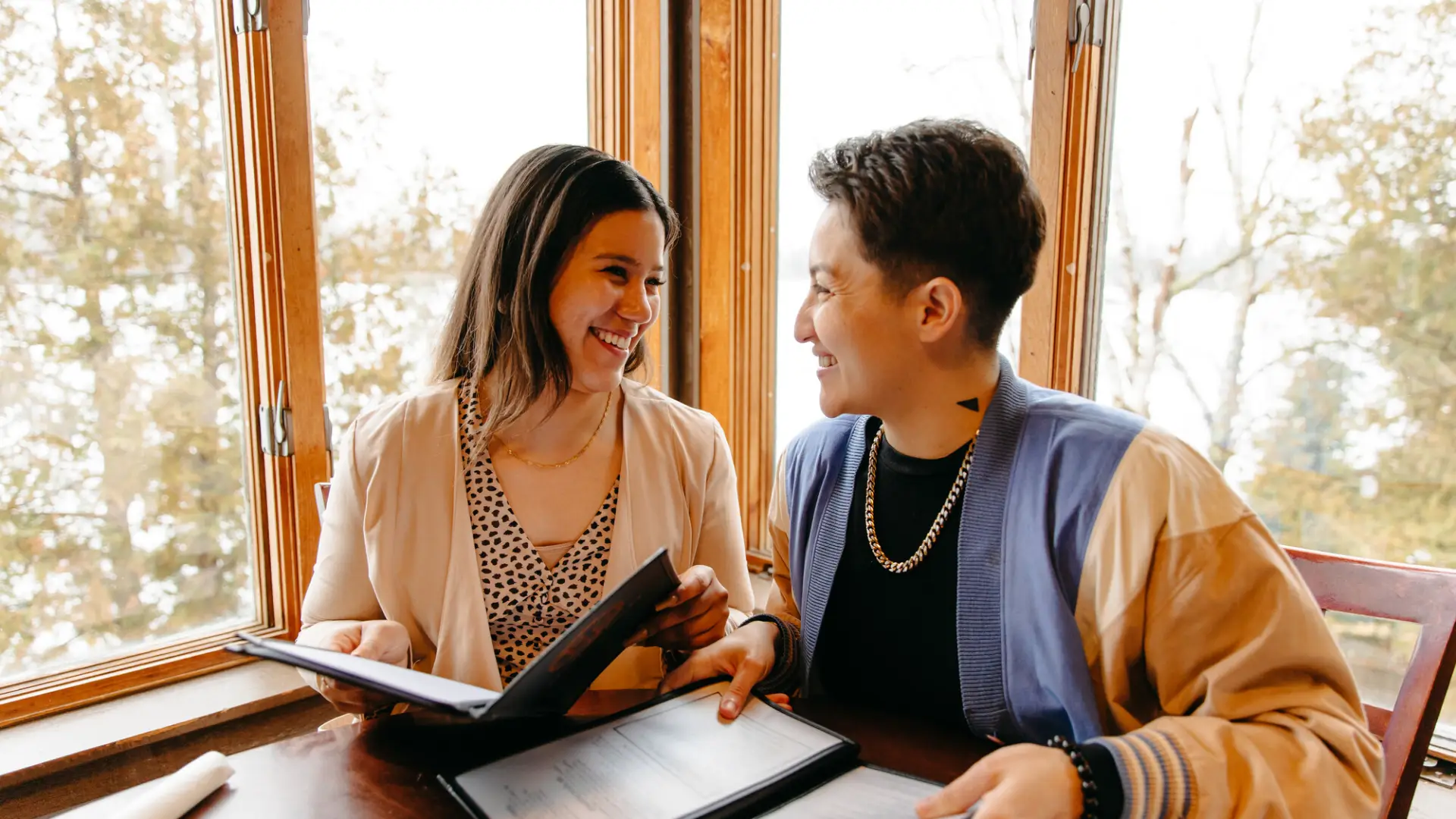 A couple smiles at one another while holding menus