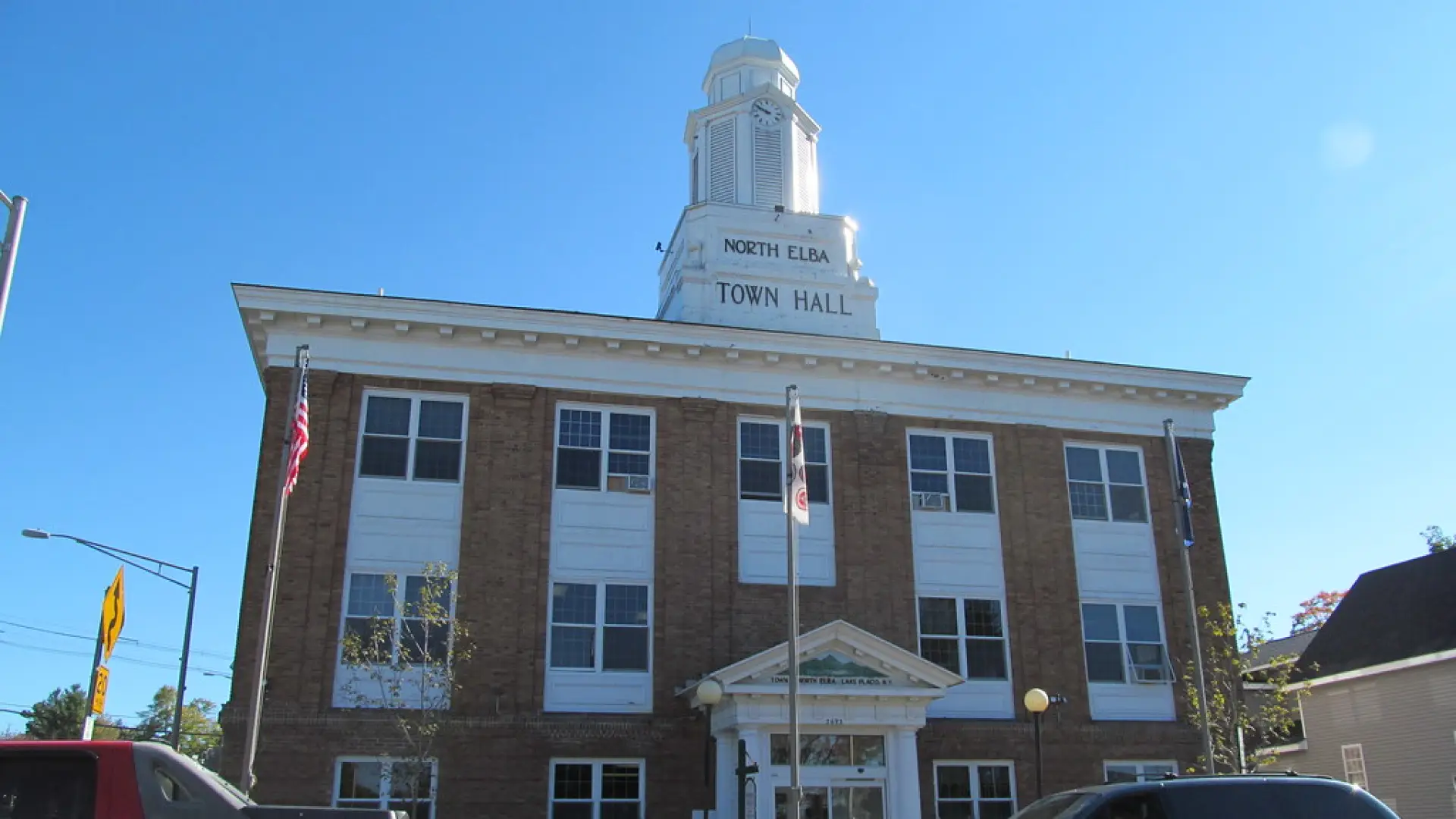Looking up at the classic brick town hall with white bell tower.