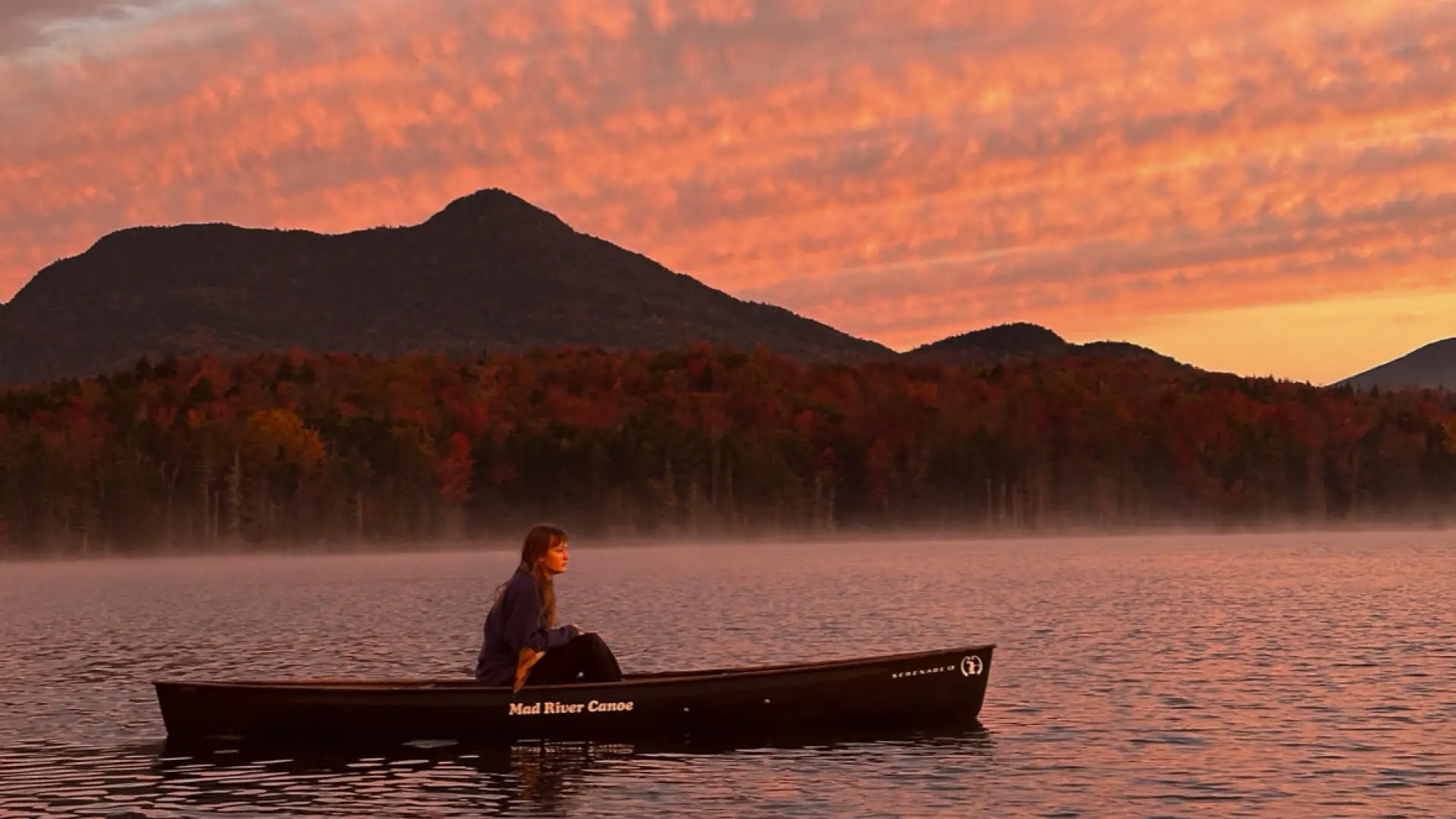 A woman paddling during sunrise.