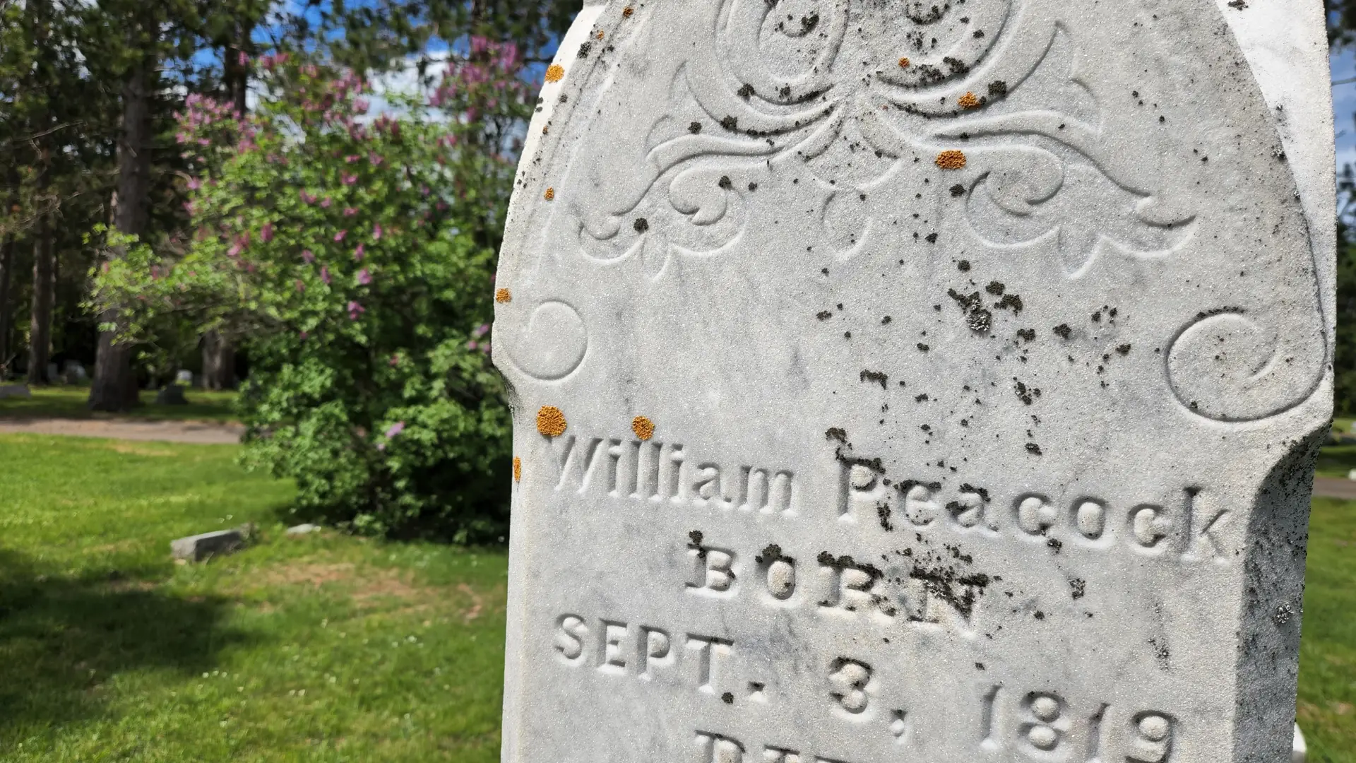 Close-up image of an old headstone with the name William Peacock and the birth date of September 3, 1819