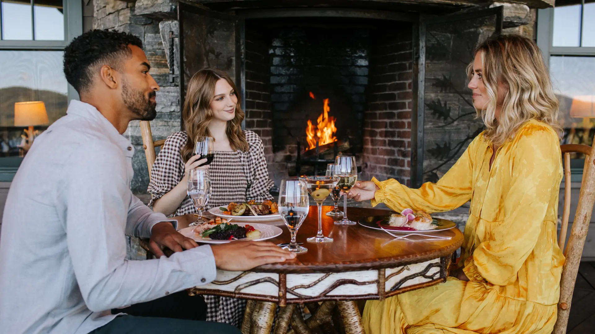 A man and woman have lunch with a woman in a yellow dress. 