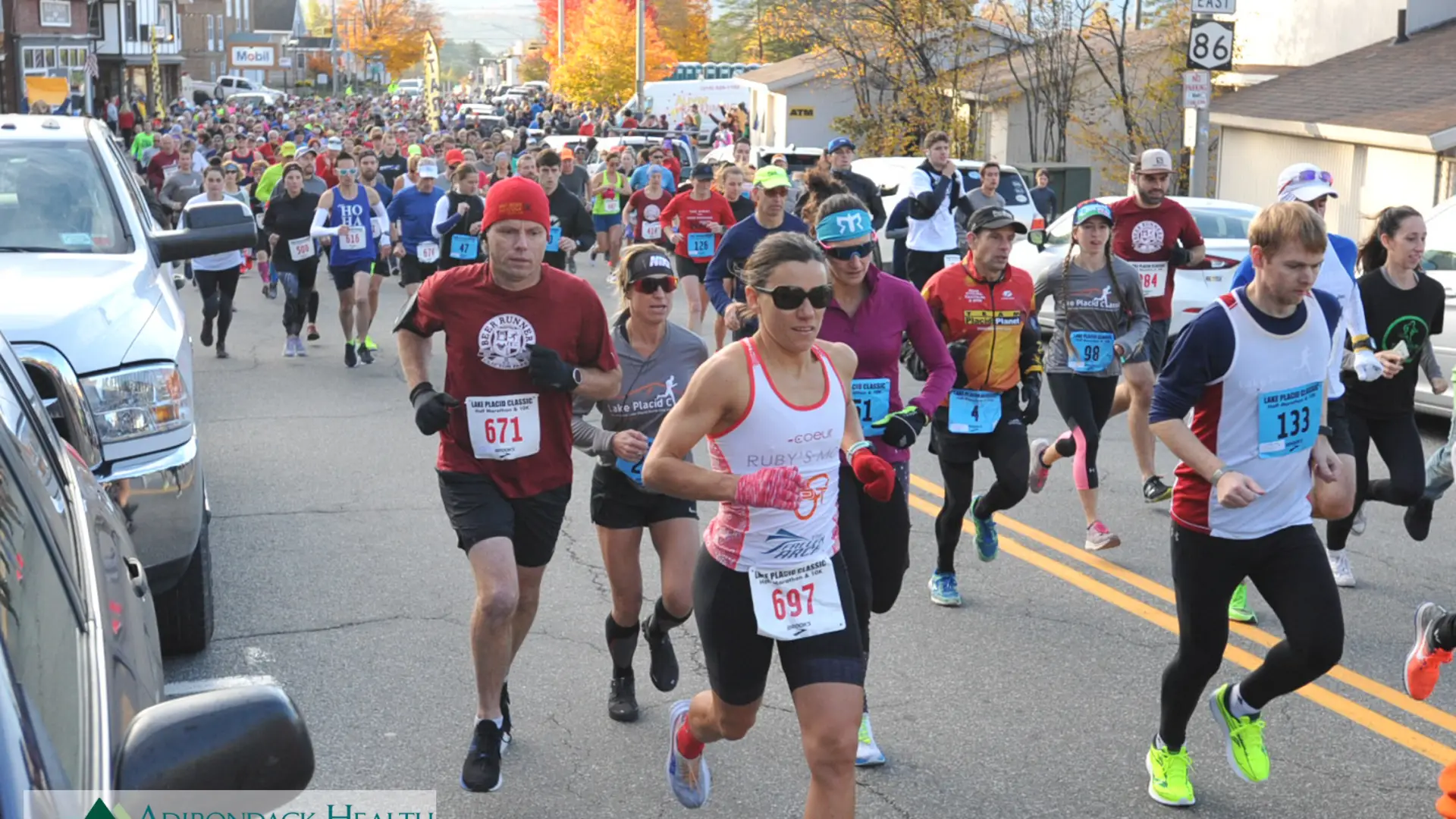 Runners race down a road aligned with fall foliage.