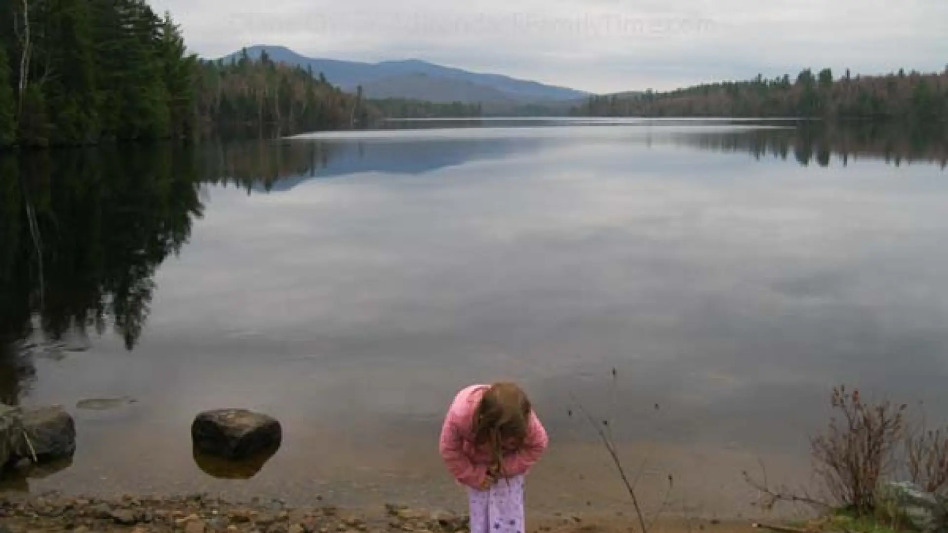 child explores shore of Franklin Falls Pond