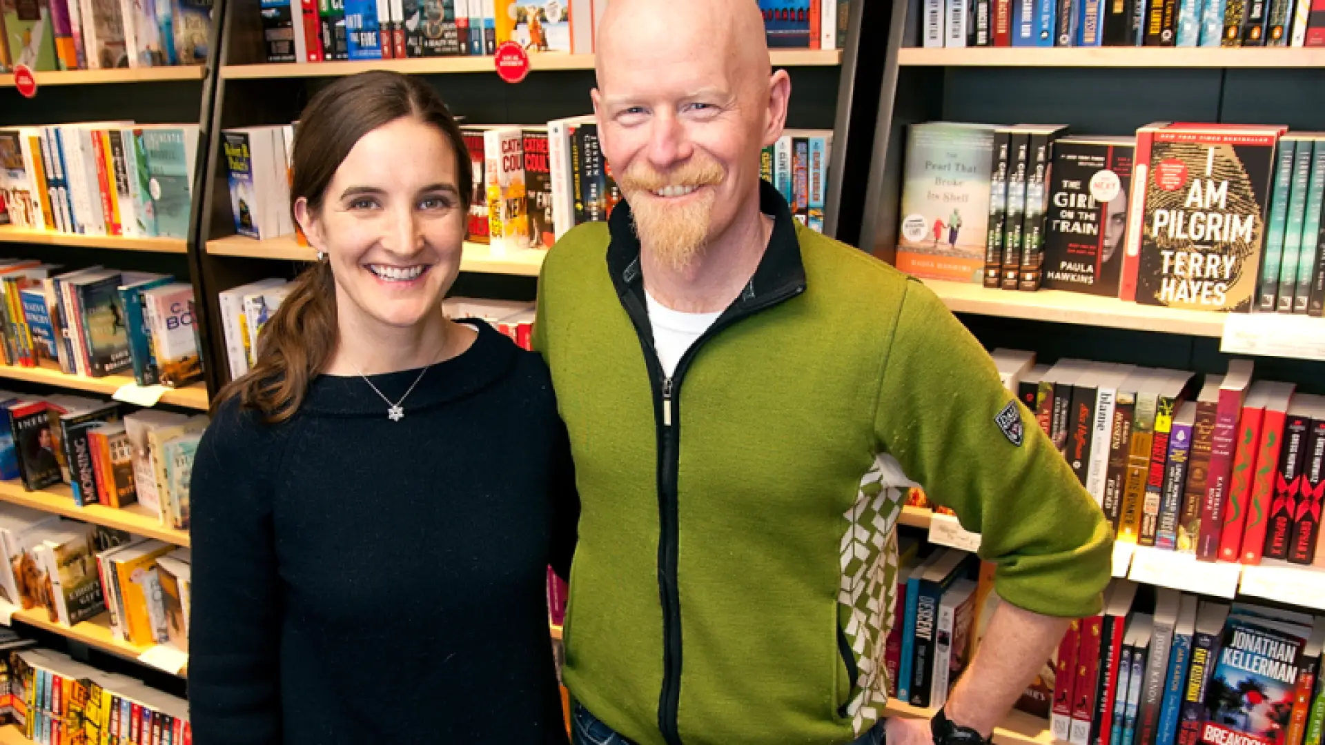 The owners of The Bookstore Plus stand in front of a display of books in their store