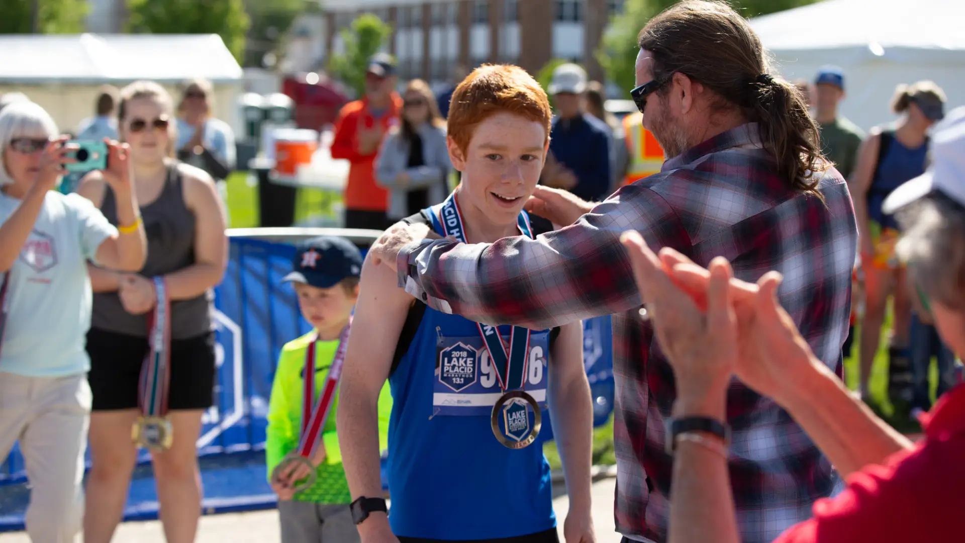A father puts a finisher medal on this sun