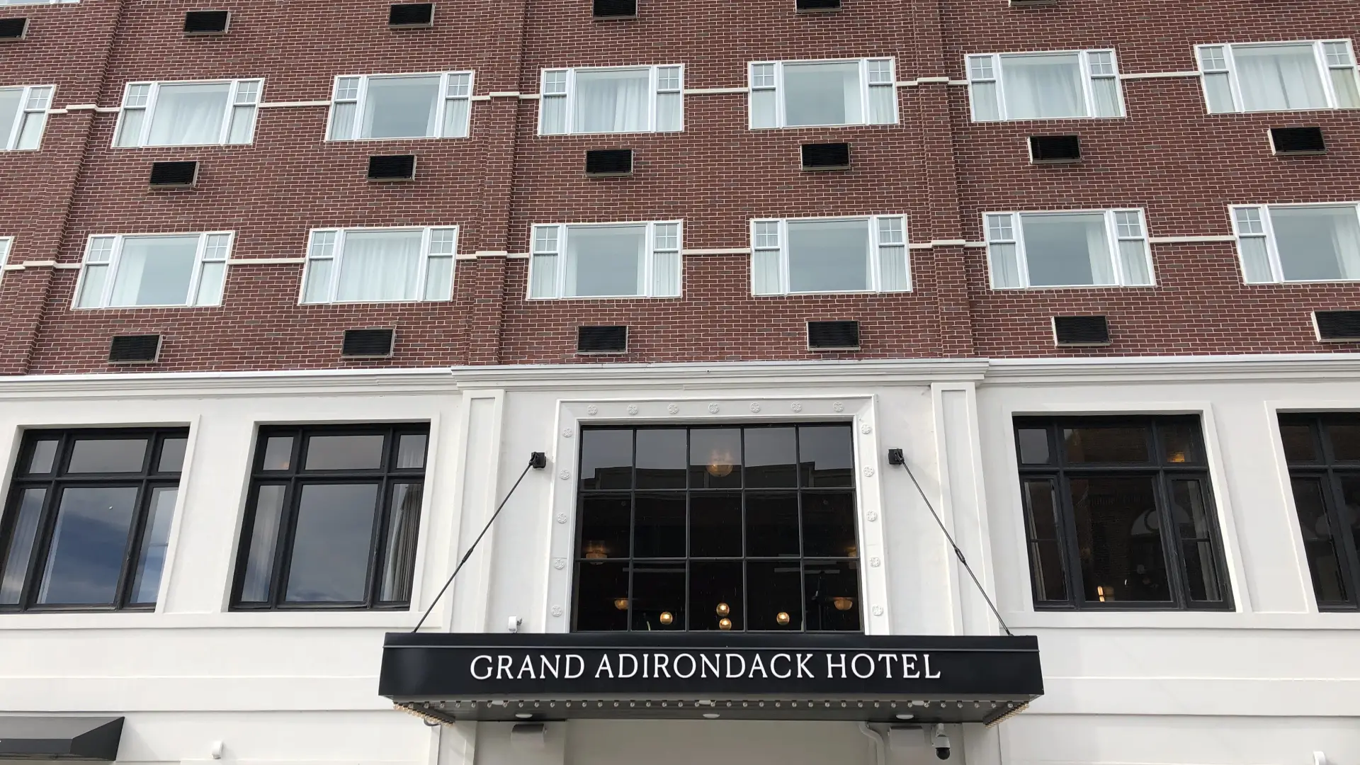 A street view of Grand Adirondack from the street with windows and front entrance sign.