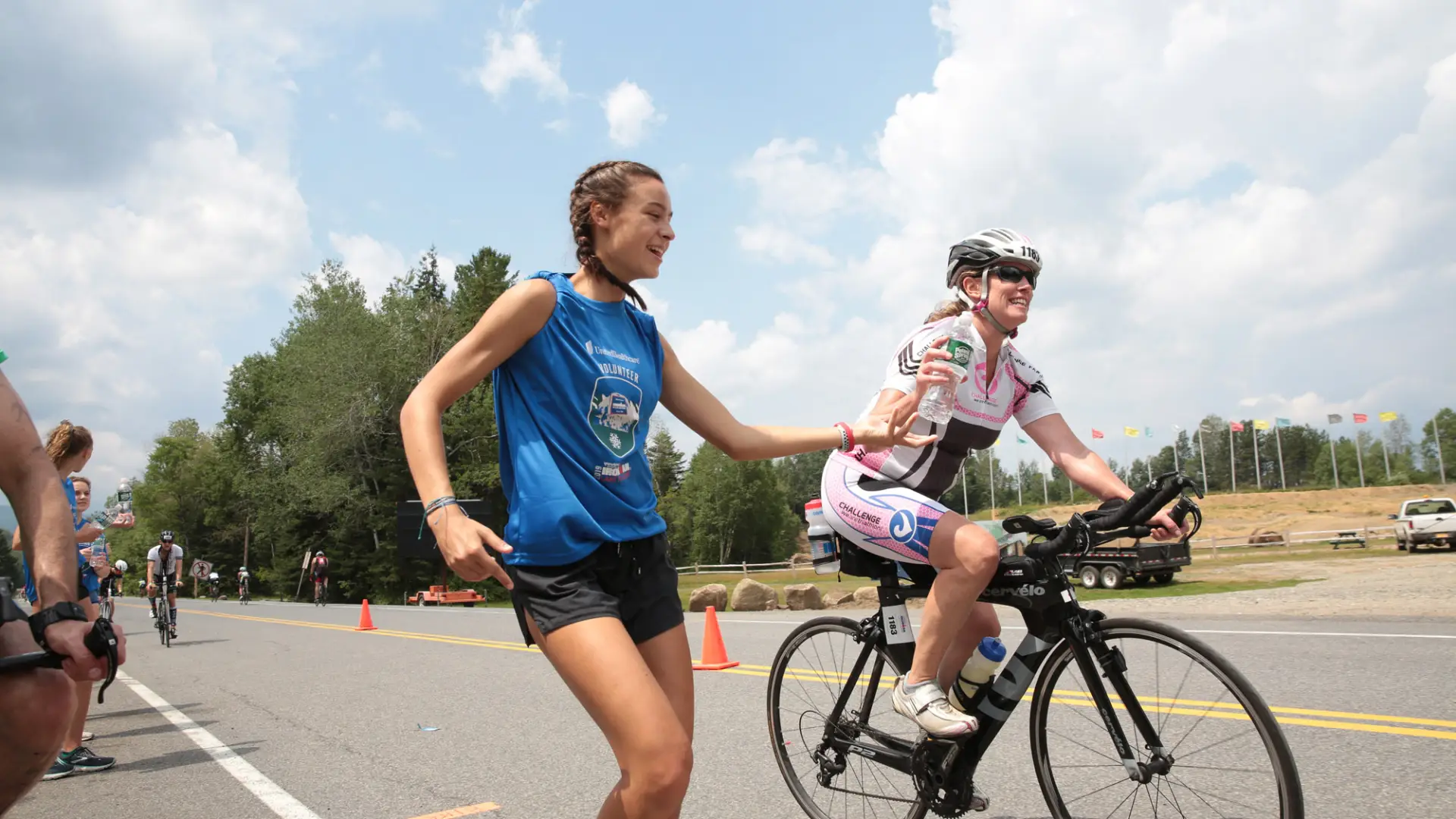 A volunteer hands off a bottle of water to a cyclist during the Ironman triathlon