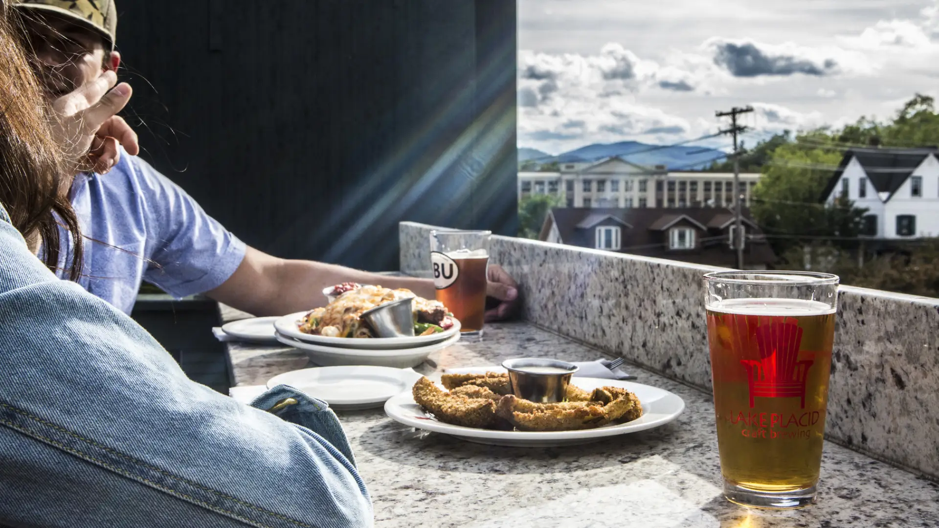 A couple eats on an outside deck with a view of the mountains in the background.