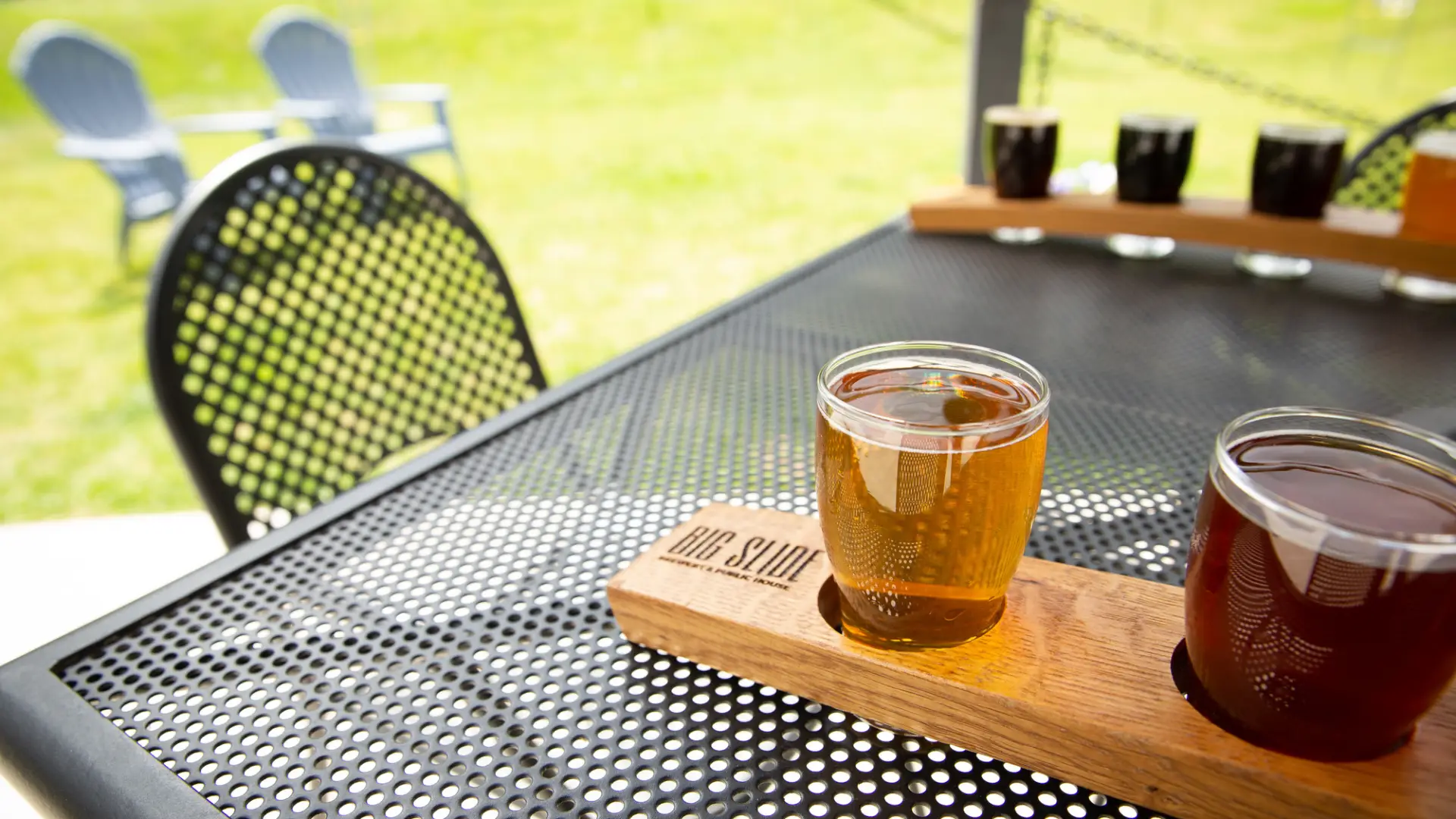 Flights of beers sit on tables outside.