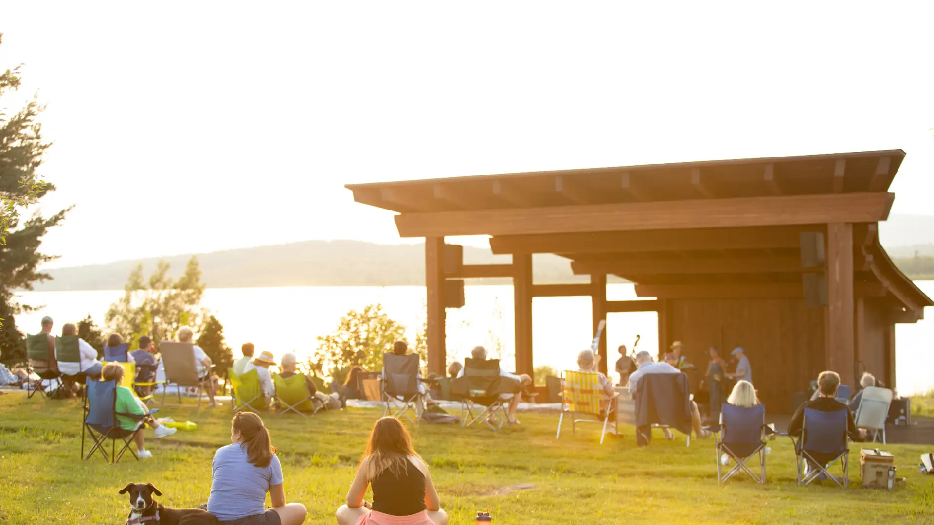 People sitting on a lawn listening to live music.