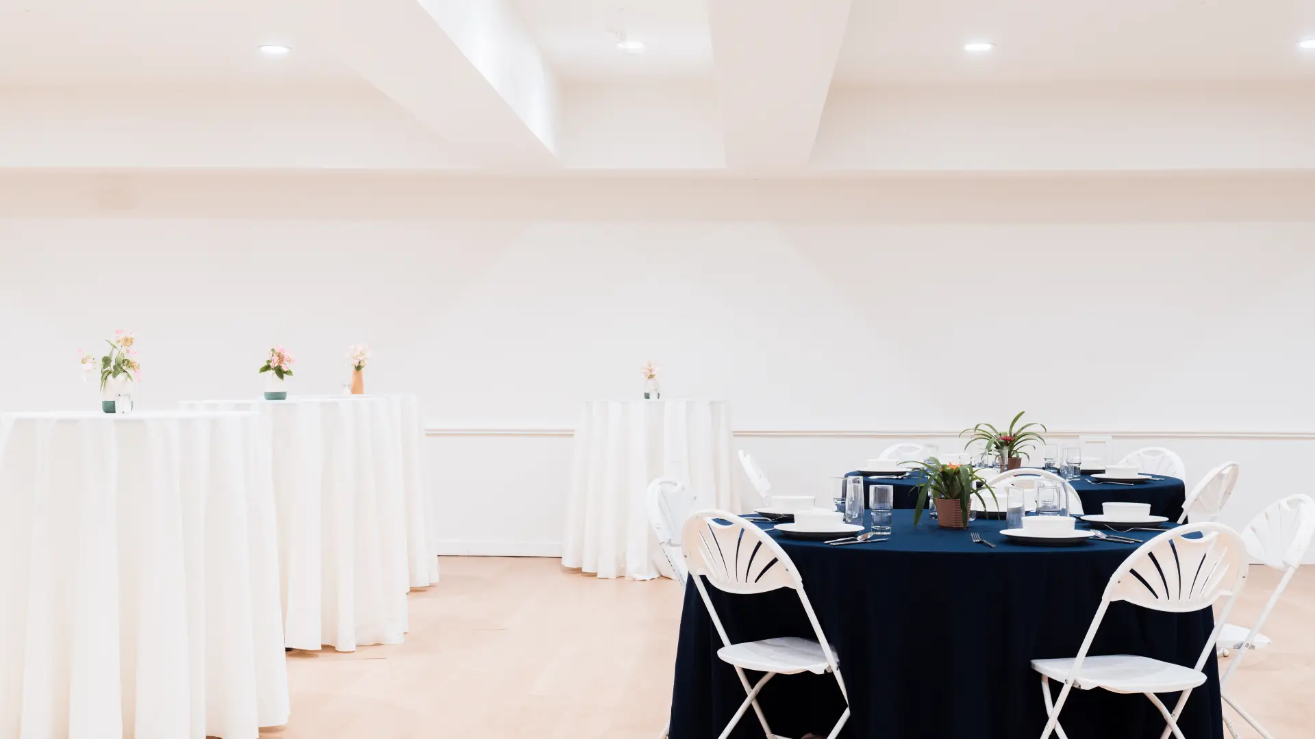 A mix of high tops and standard round tables in a bright white space.