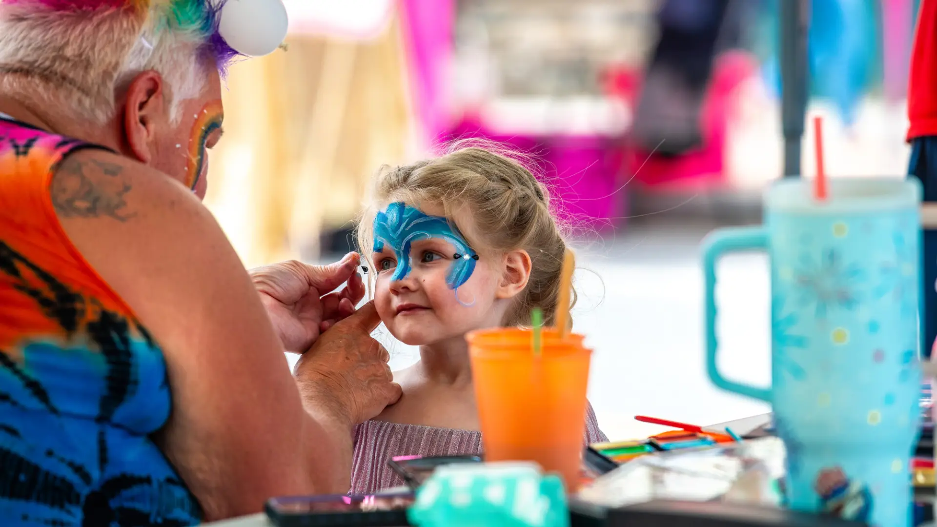 A young child gets their face painted.