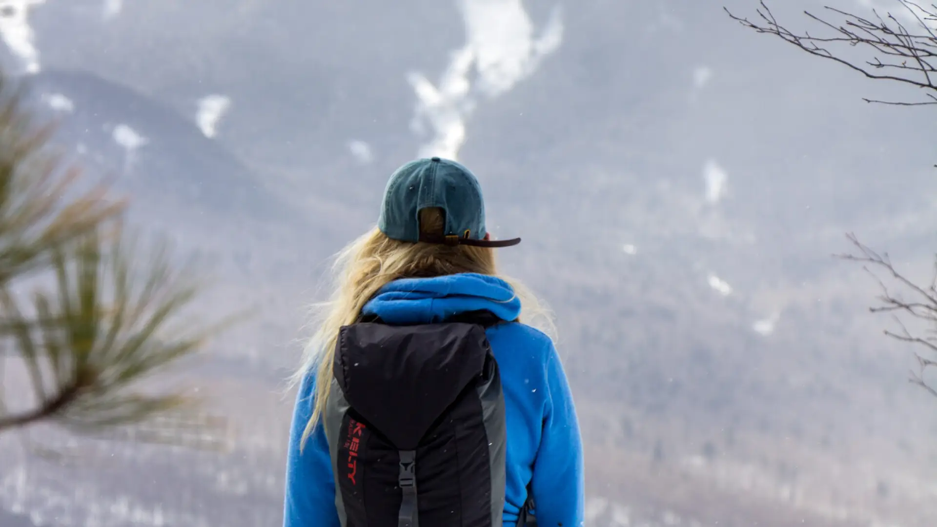 A woman standing at the summit of a winter hike.