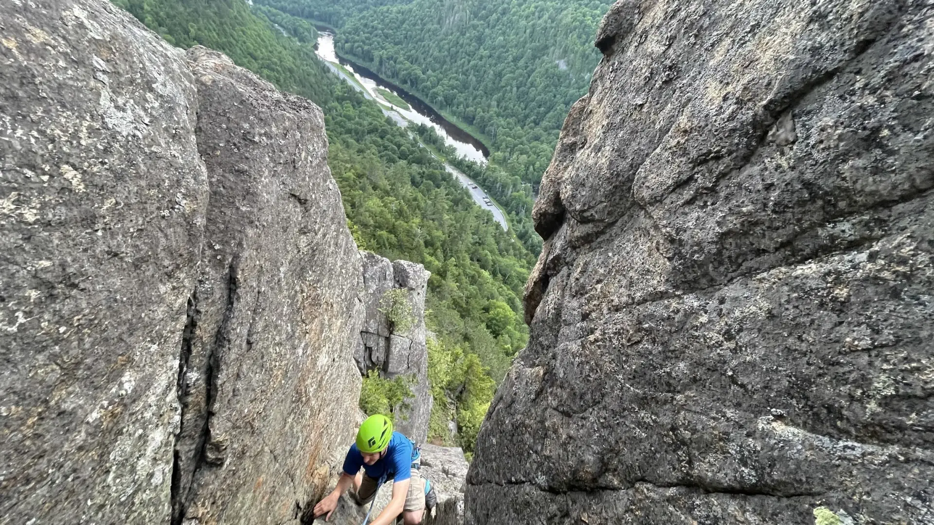 a rock climber ascends a crevice in the mountainside