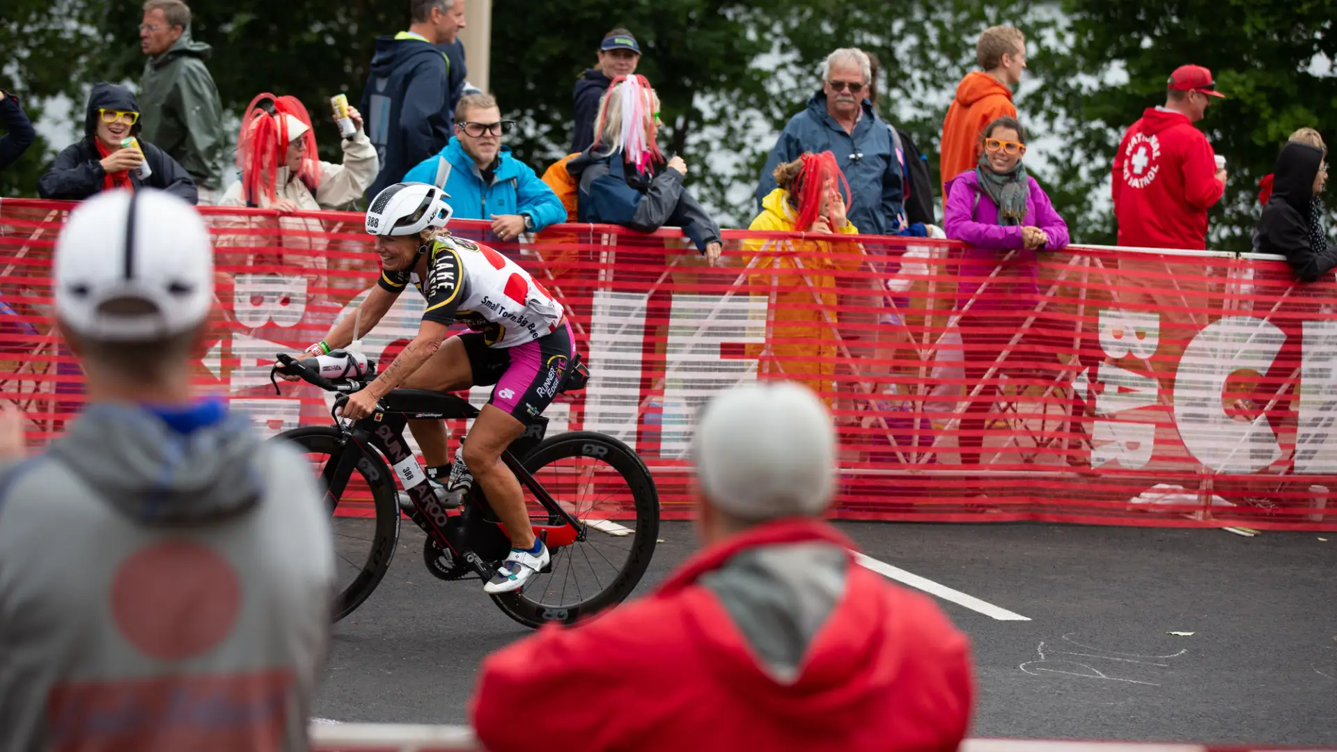 An athlete biking by a large crowd.