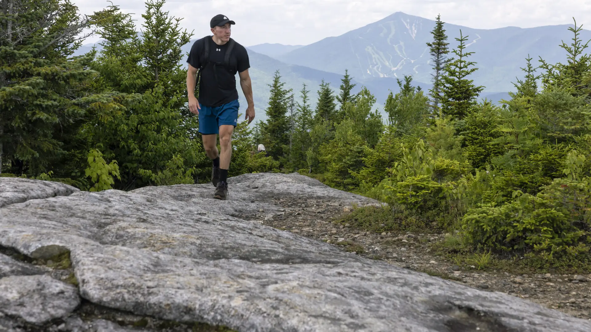 A hiker walks on a rocky surface on a mountain
