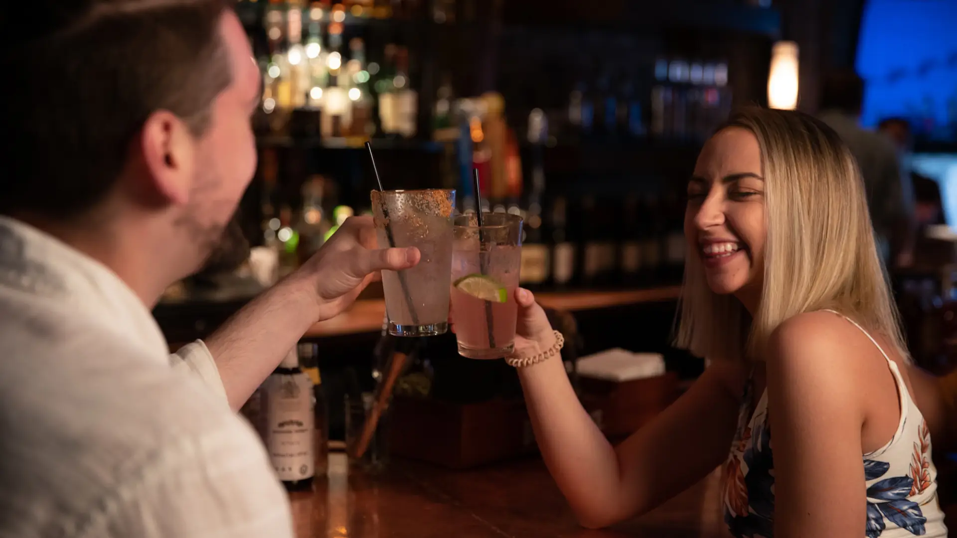 A man and woman share drinks at a bar.