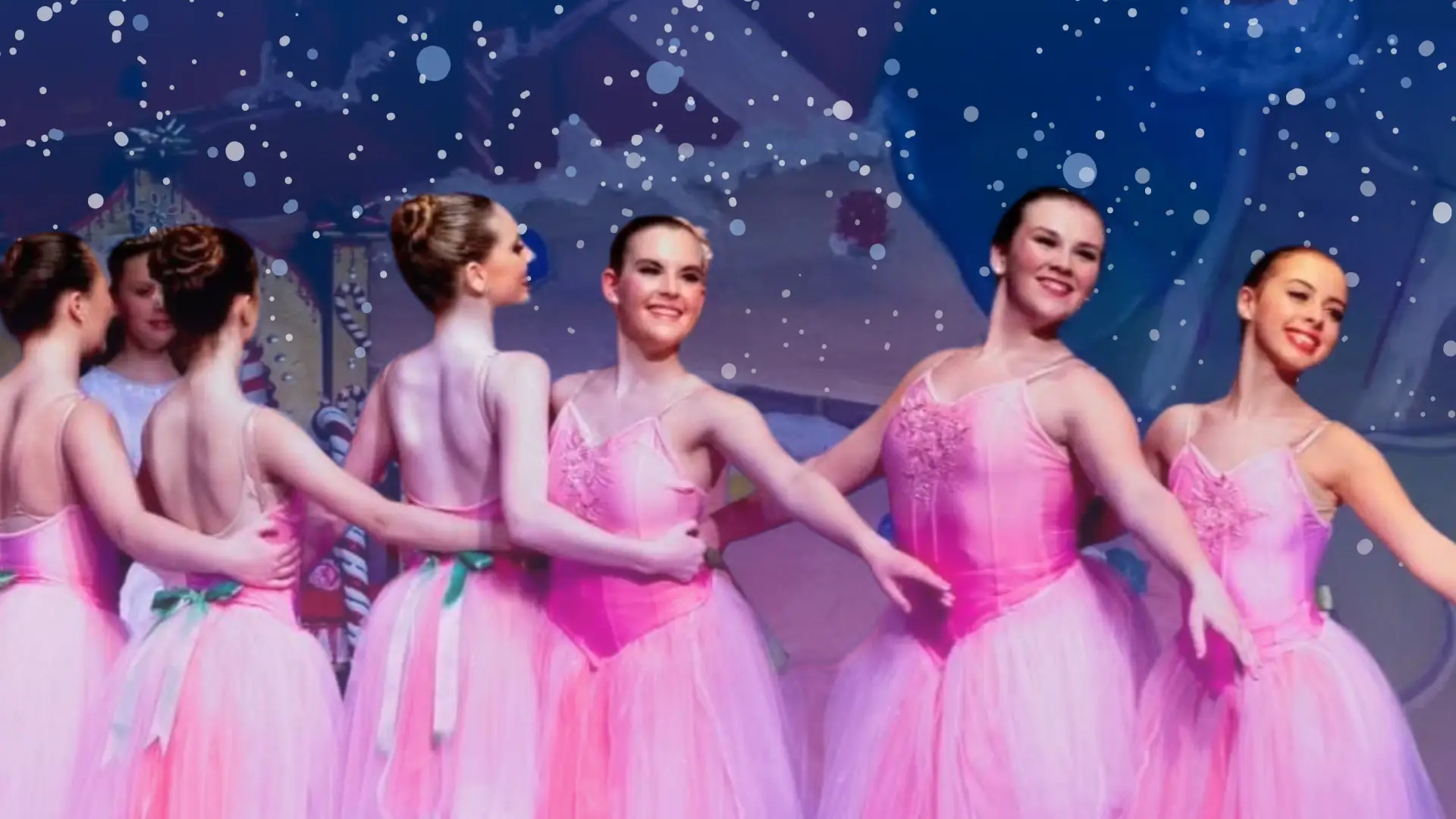 Group of young female ballerinas in pink dress costumes dance on stage with arms around one another