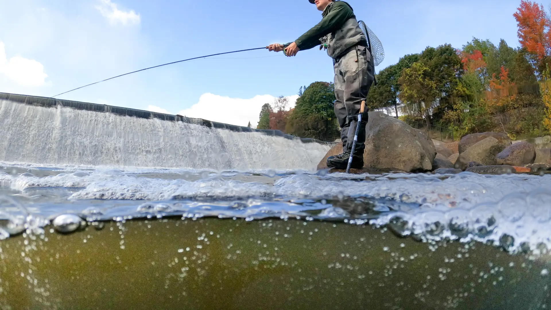 A man fishing under a dam